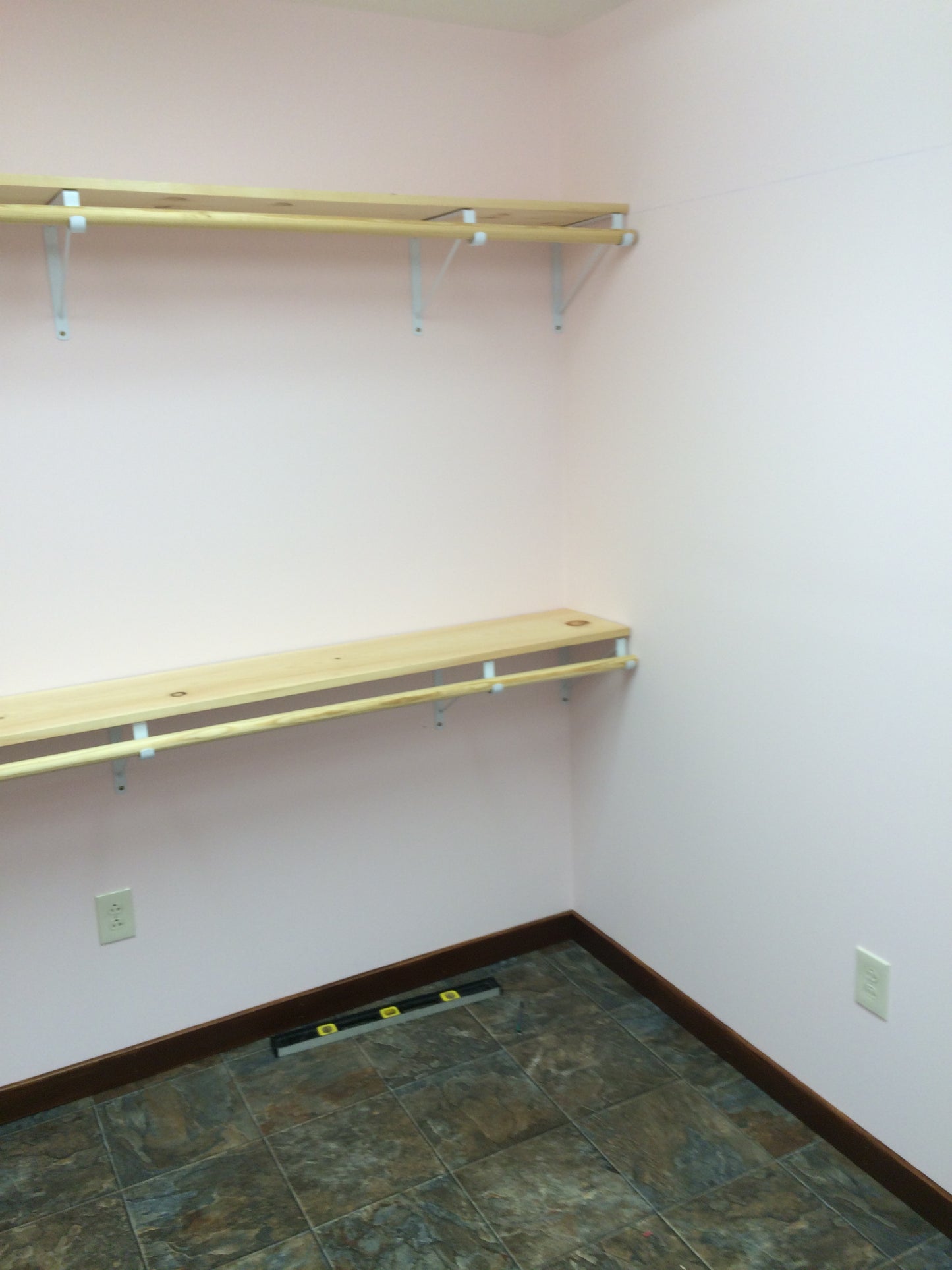 Two wooden shelves against a wall with a tiled floor.