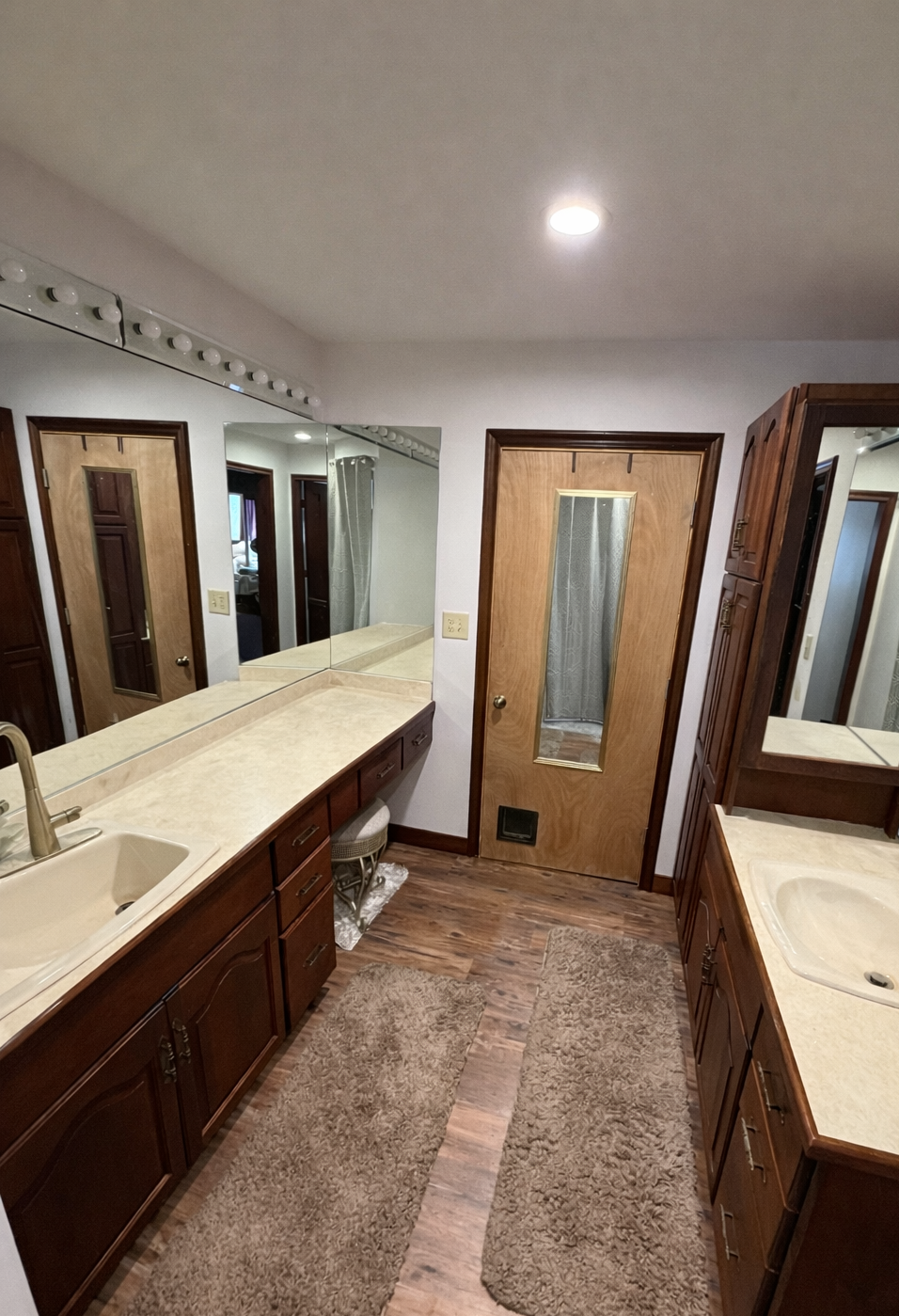 Bathroom with double vanity, mirrors, and wooden doors.