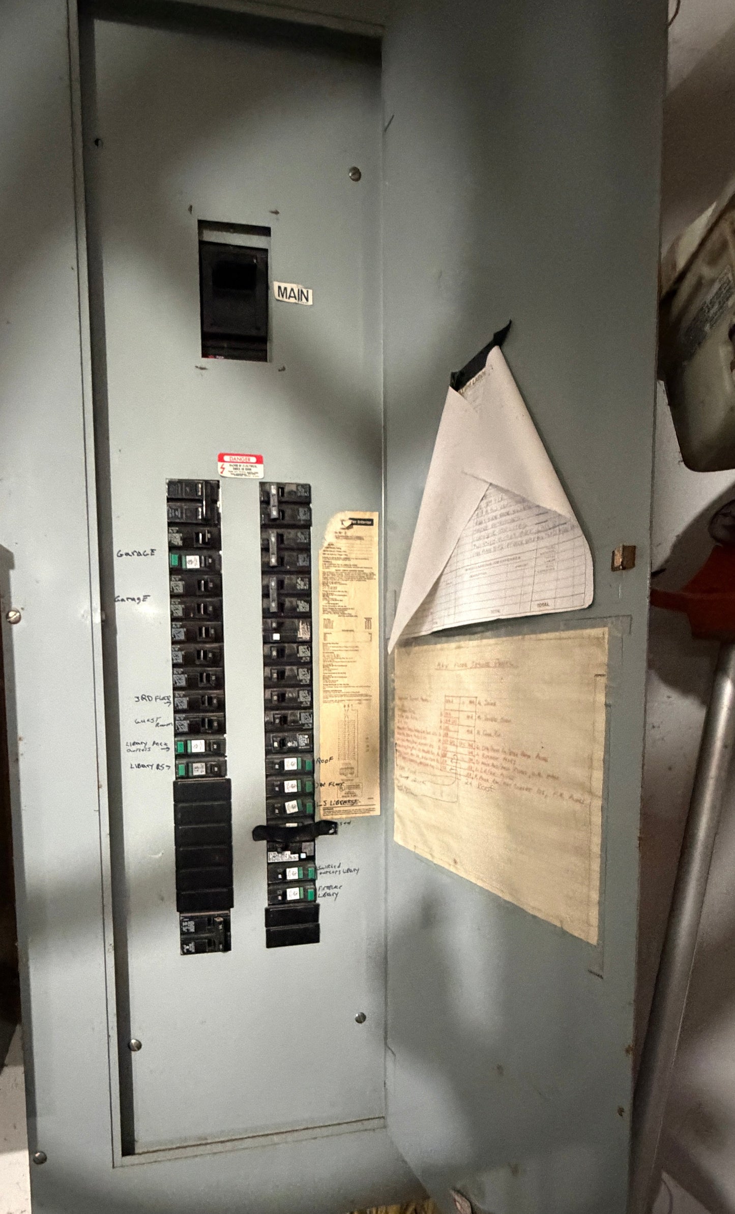 Electrical panel with circuit breakers and labels on a metallic surface.