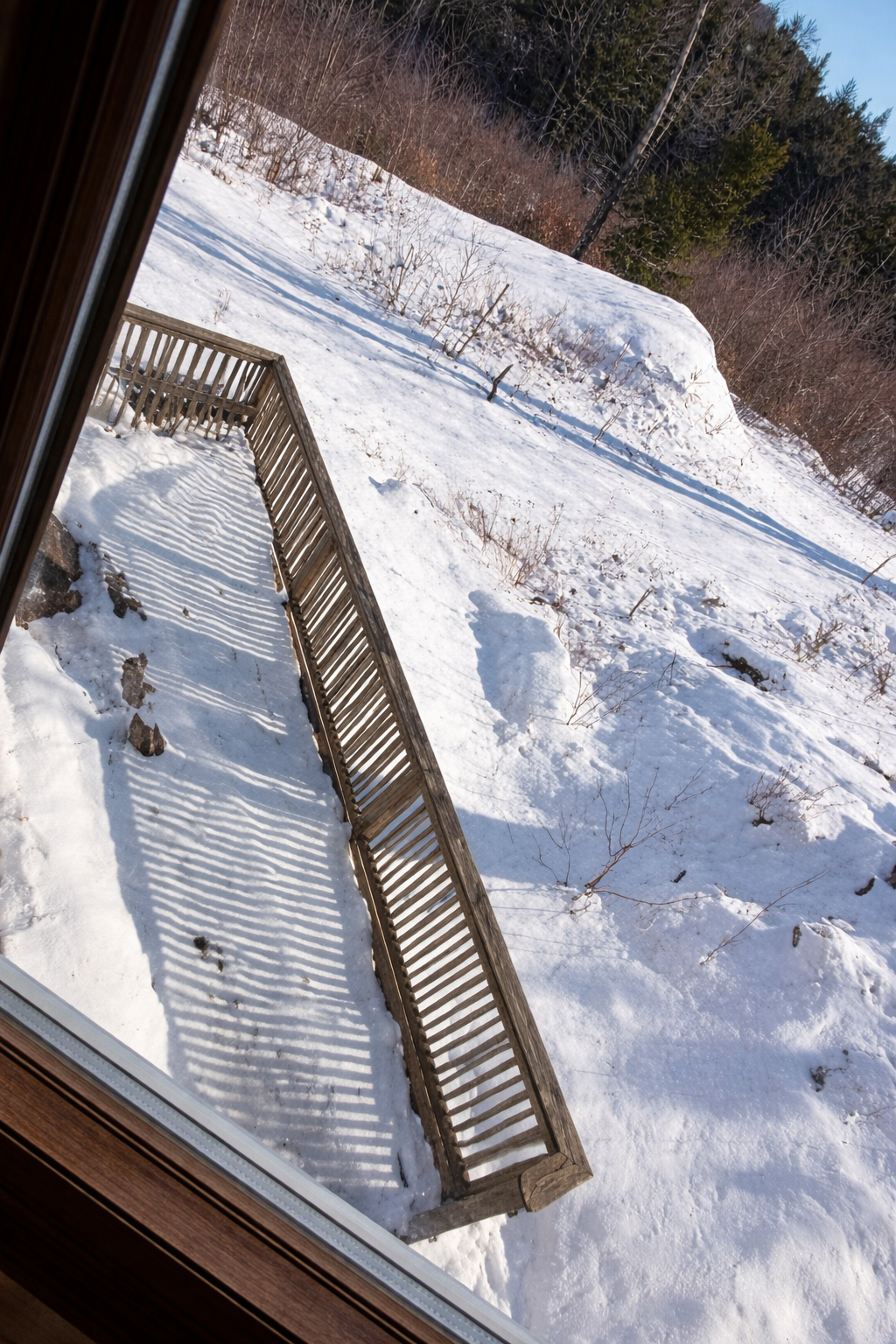 Wooden deck leading down to a snowy landscape with trees in the background.