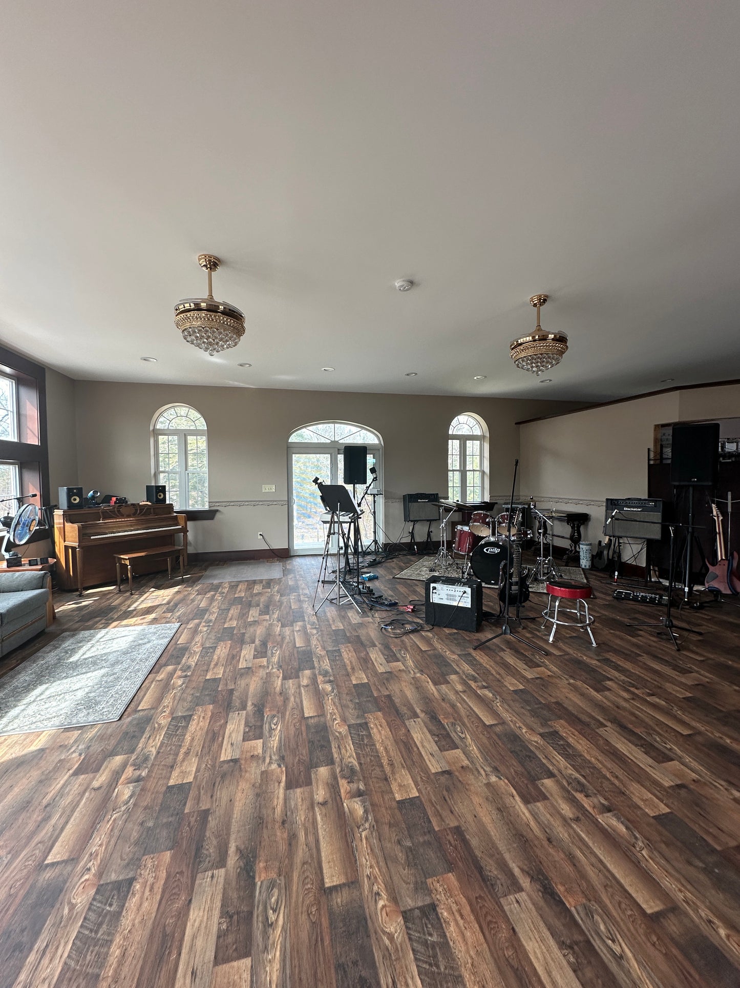 Large practice room with wooden flooring, white walls, and a piano in the corner.