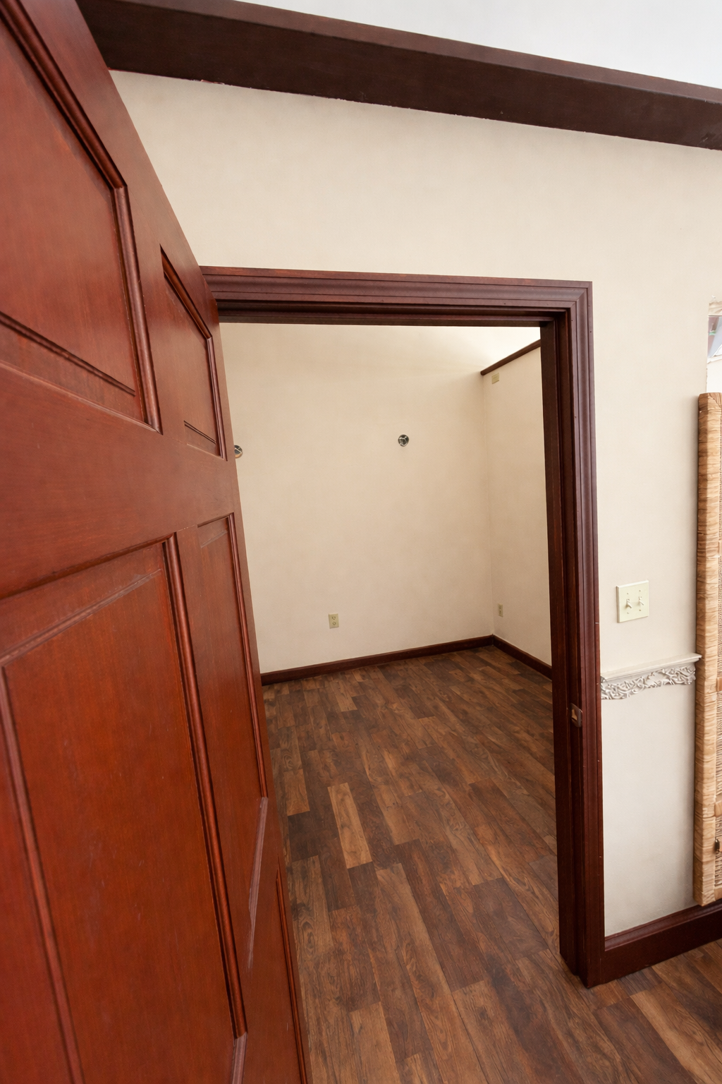 Wooden door with a large room with wooden floor and white walls.