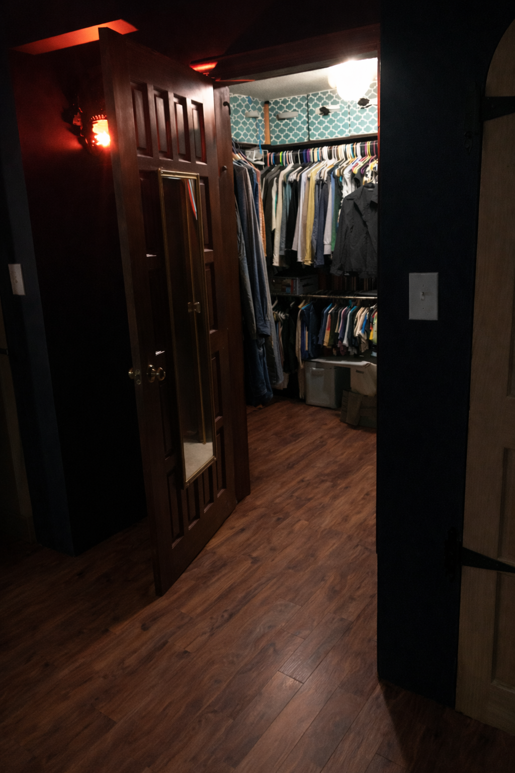 Closet with hanging clothes and shelves in a dimly lit room