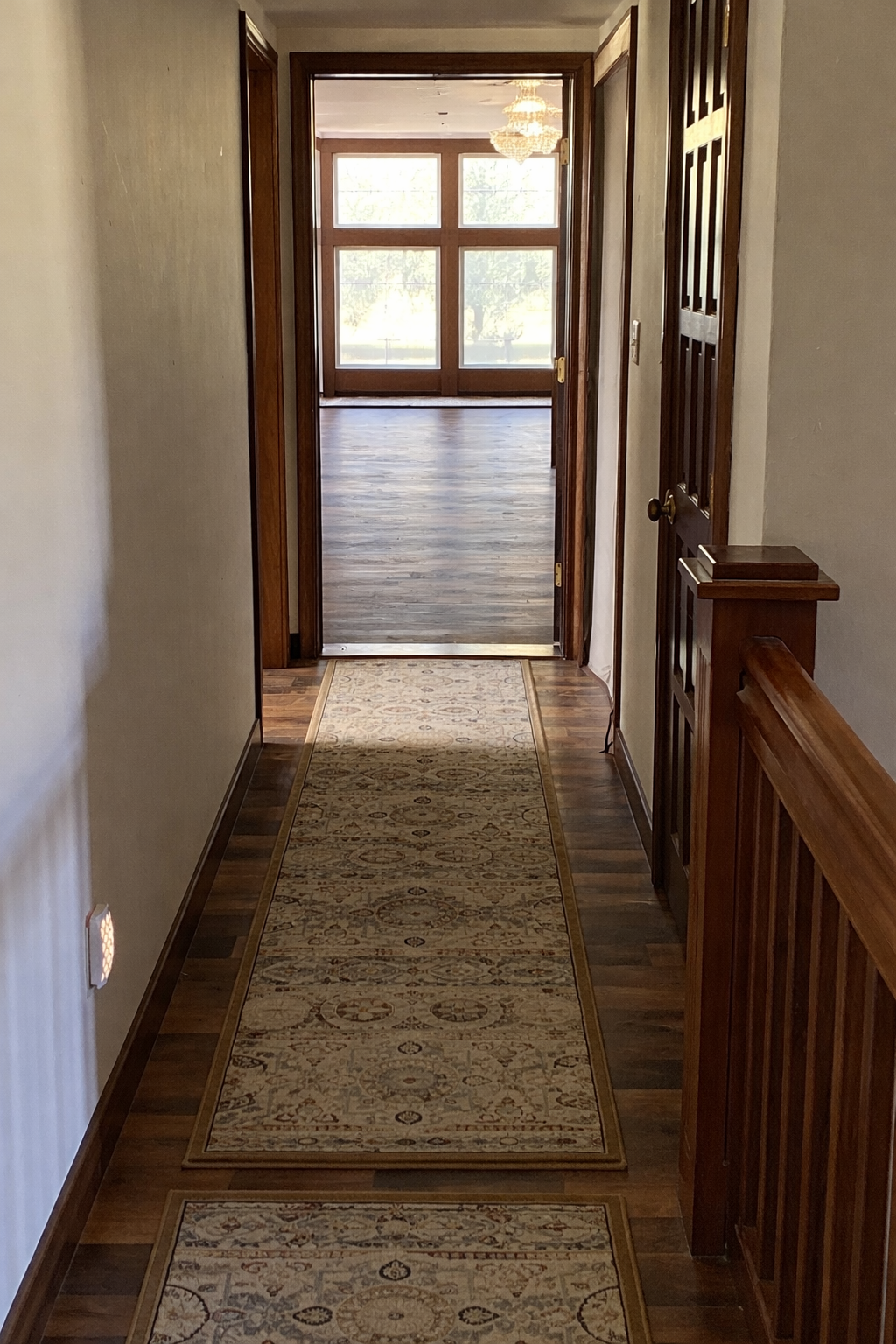 Hallway with a patterned rug leading to an open door with a view of the library.