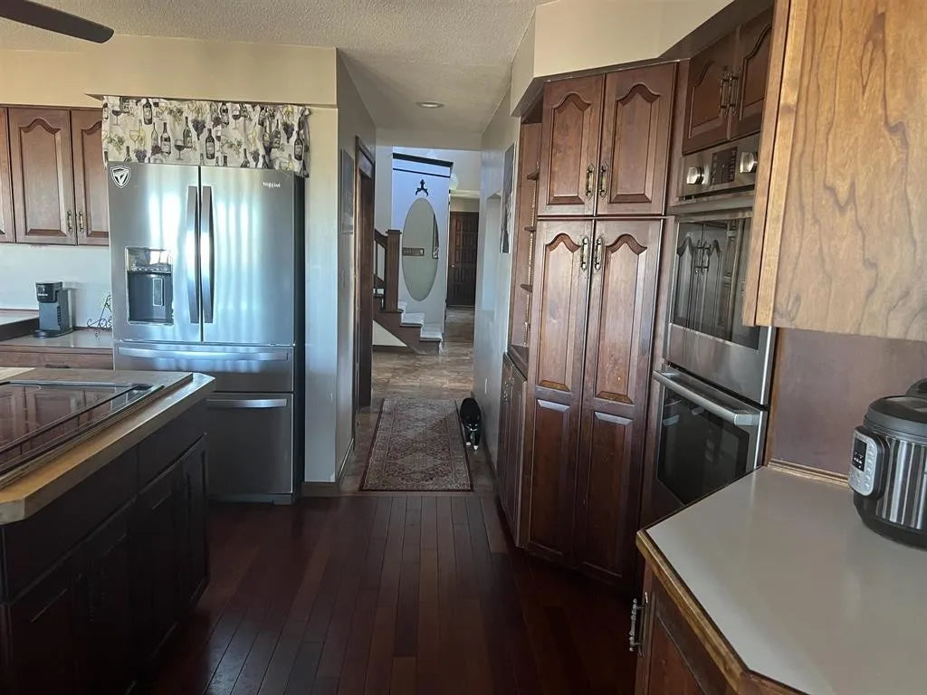 Kitchen with wooden cabinets, stainless steel appliances, and cherry flooring.