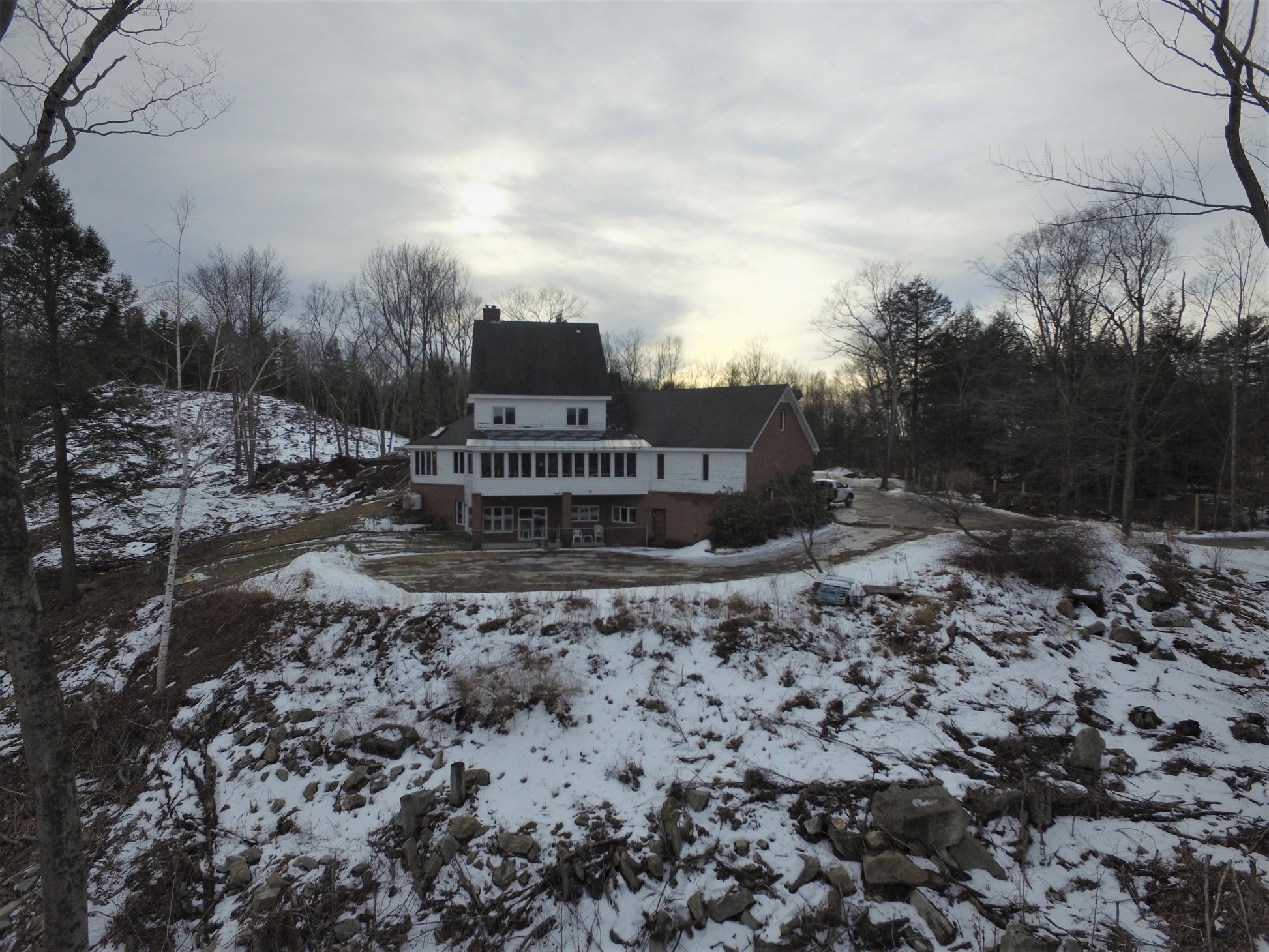 Large house with a snowy landscape and trees in the foreground