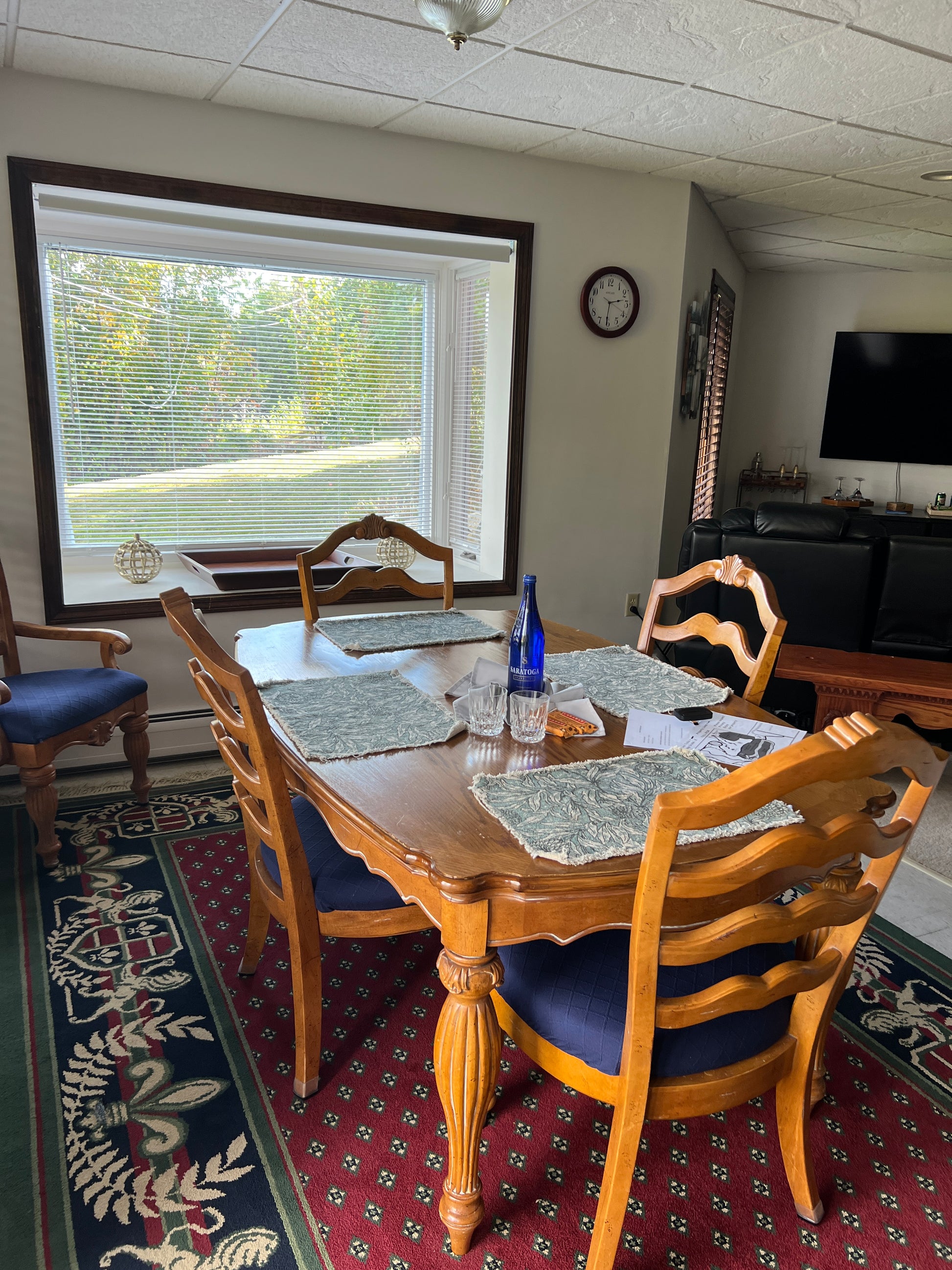 Dining room with wooden chairs, table, and a clock on the wall.