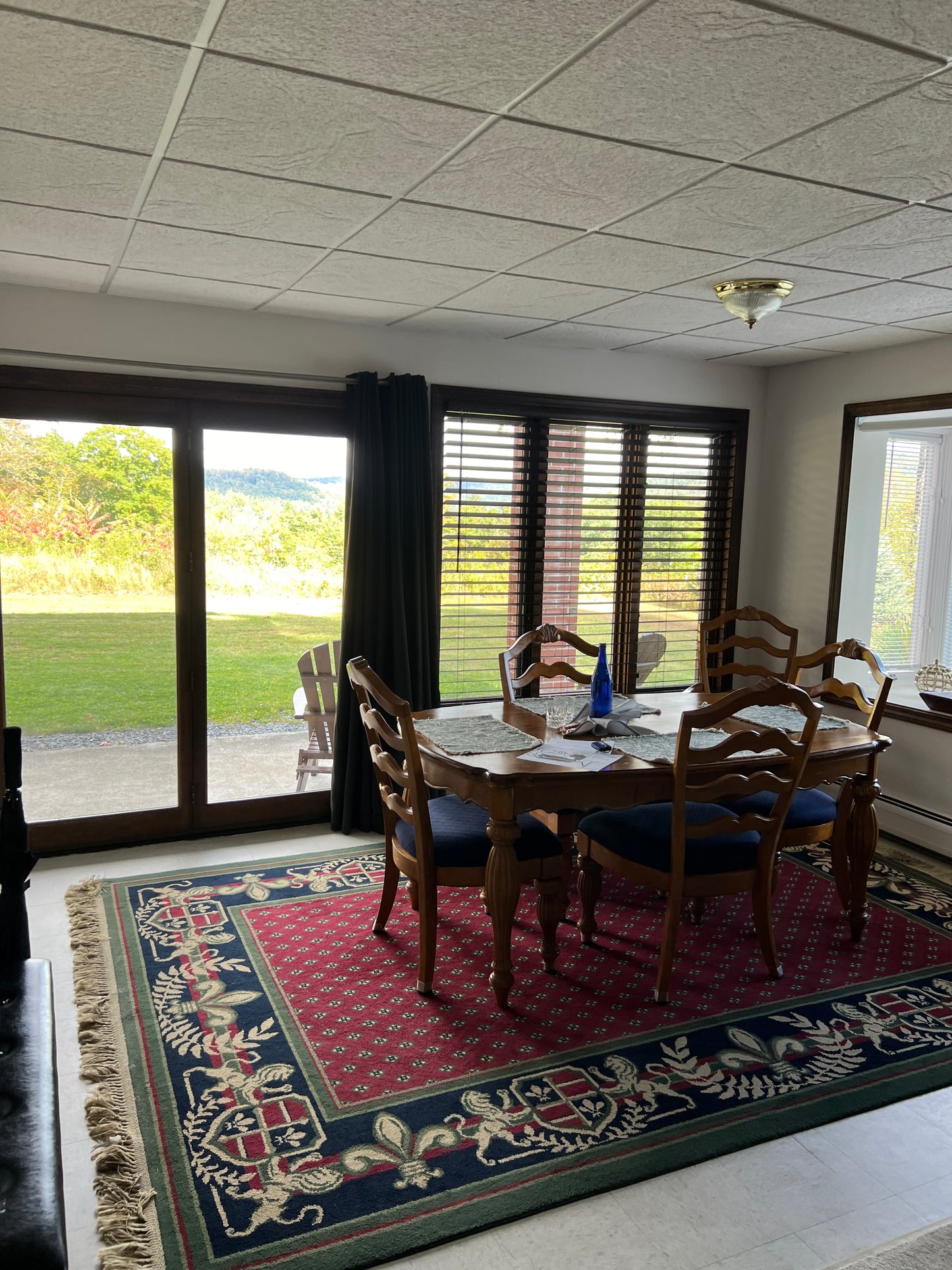 Dining room with wooden table and chairs near a large window with blinds.