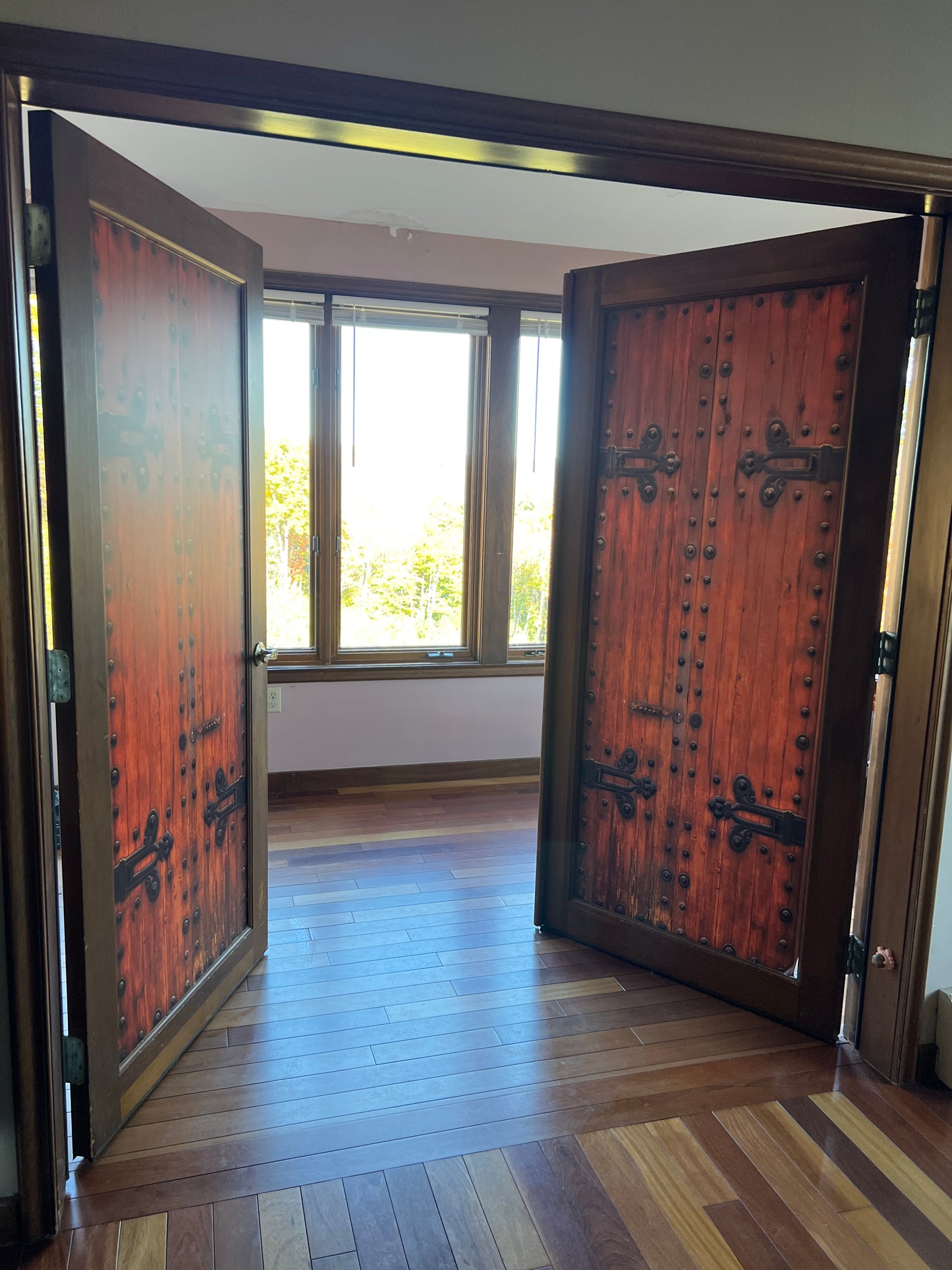 sunshine just outside the pen doors revealing a wooden floor an mahogany and cherry room interior.