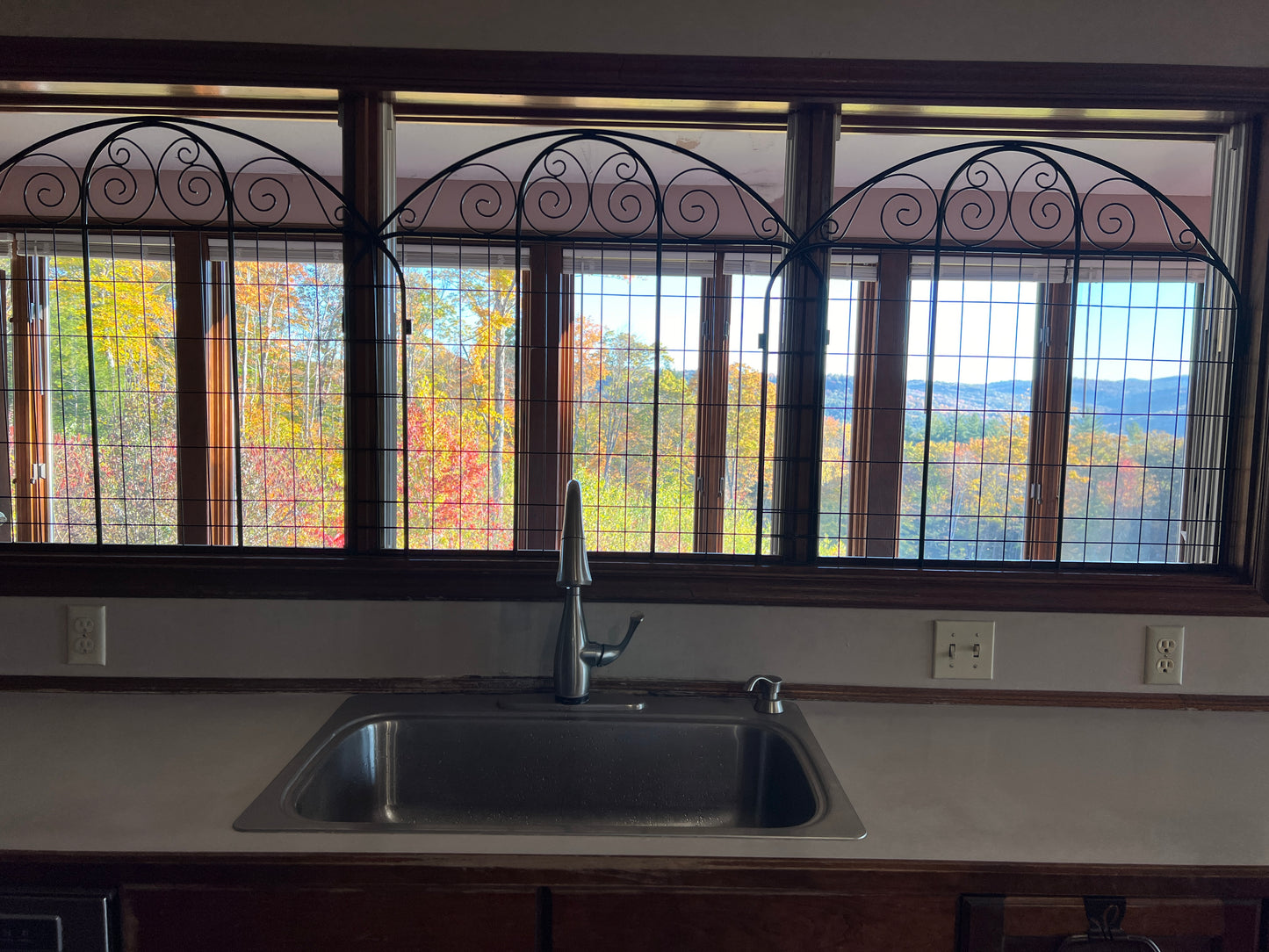 Kitchen sink with decorative window above showing autumn foliage
