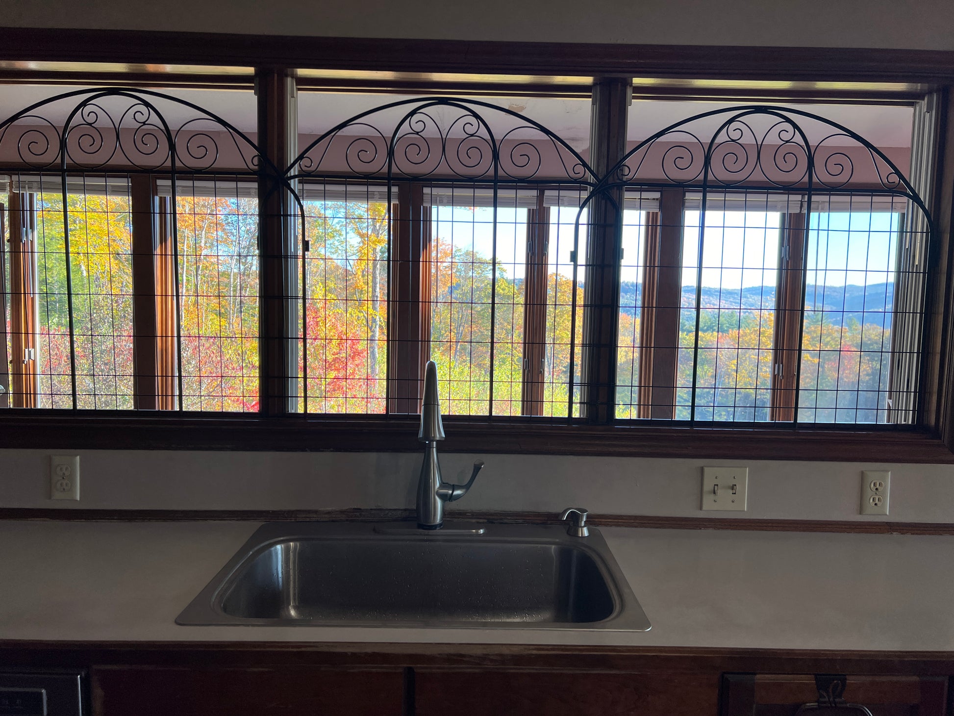 Kitchen sink with decorative window above showing autumn foliage