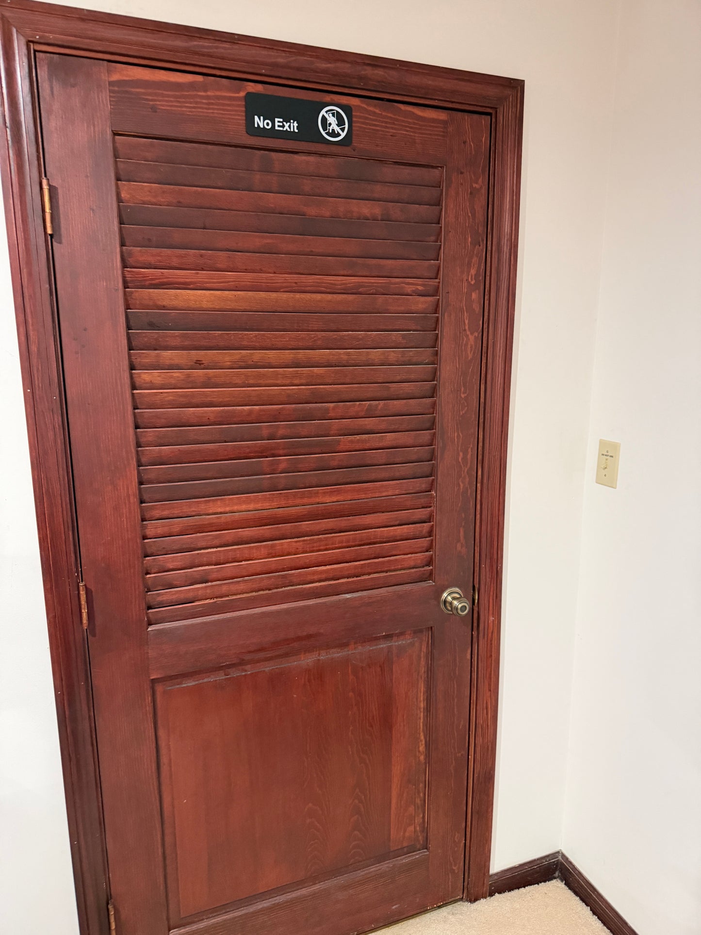 Wooden door with a 'No Exit' sign on  wall