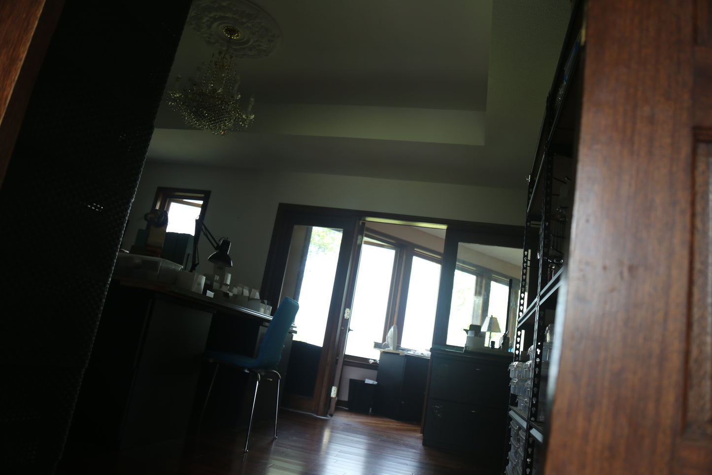 Darkly lit room with wooden furniture looking out to the view reflecting back into the  interior.