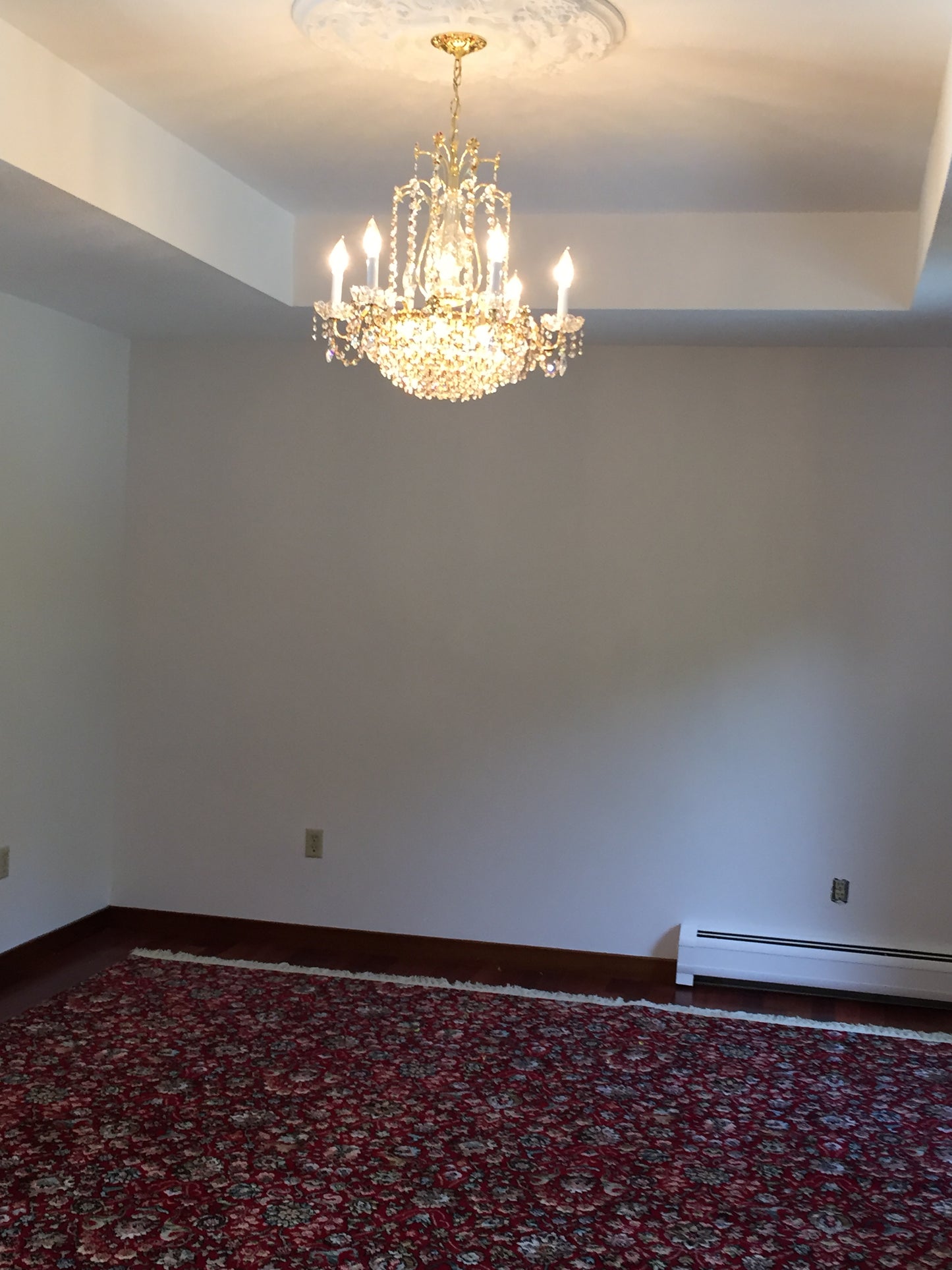 Chandelier hanging from a ceiling in a room with a patterned wall.