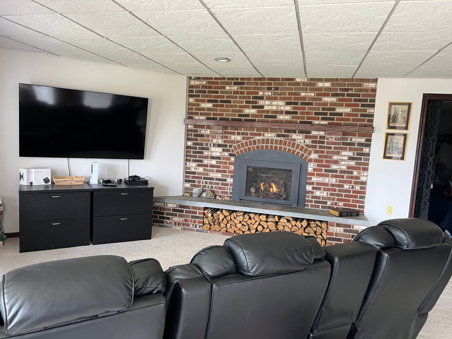Living room with black leather sofa, TV, and brick fireplace.