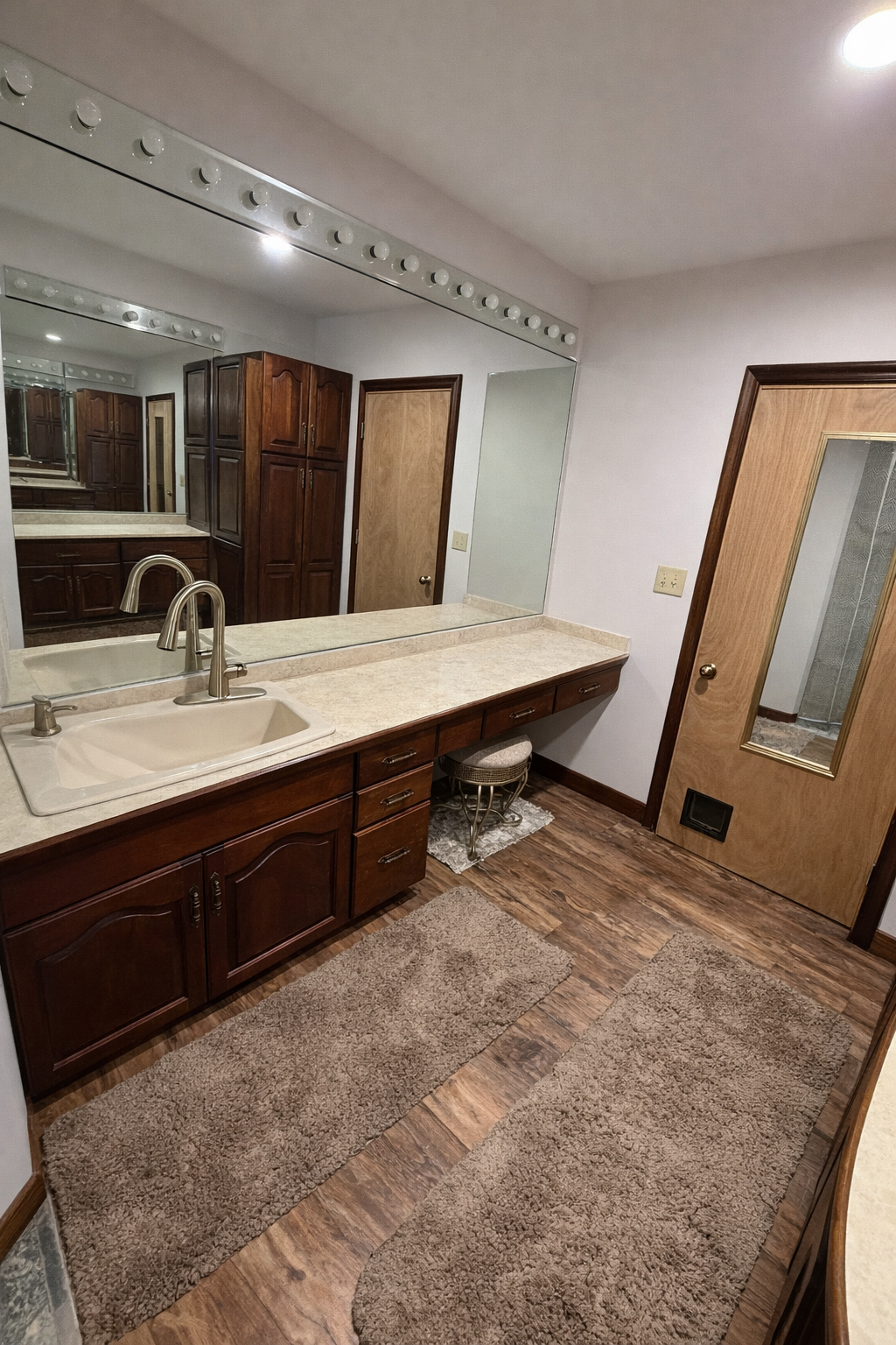 Bathroom with large mirror, sink, and wooden cabinets.