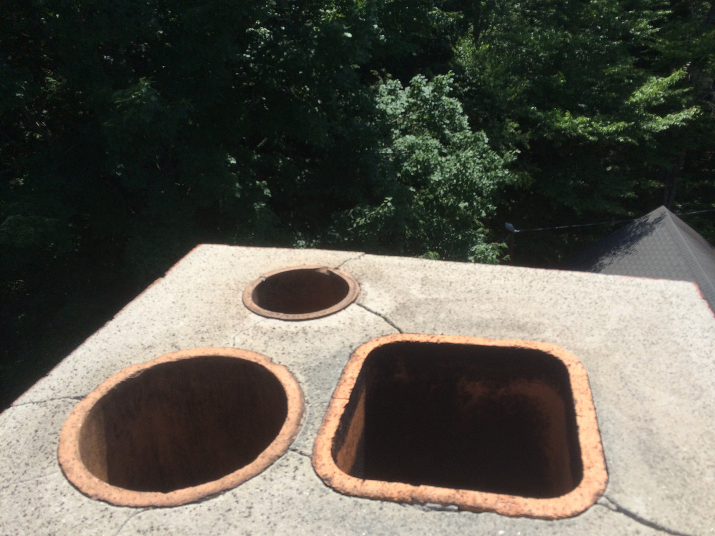 Chimney top Three circular holes in a concrete surface with trees in the background
