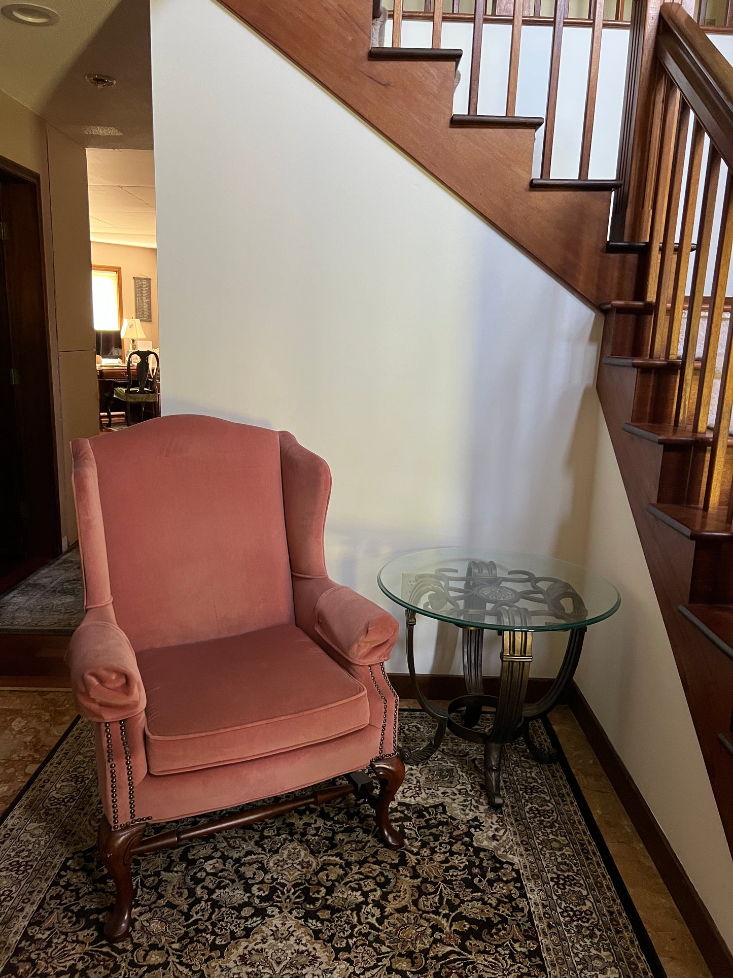 Pink armchair in a room with a staircase and patterned rug