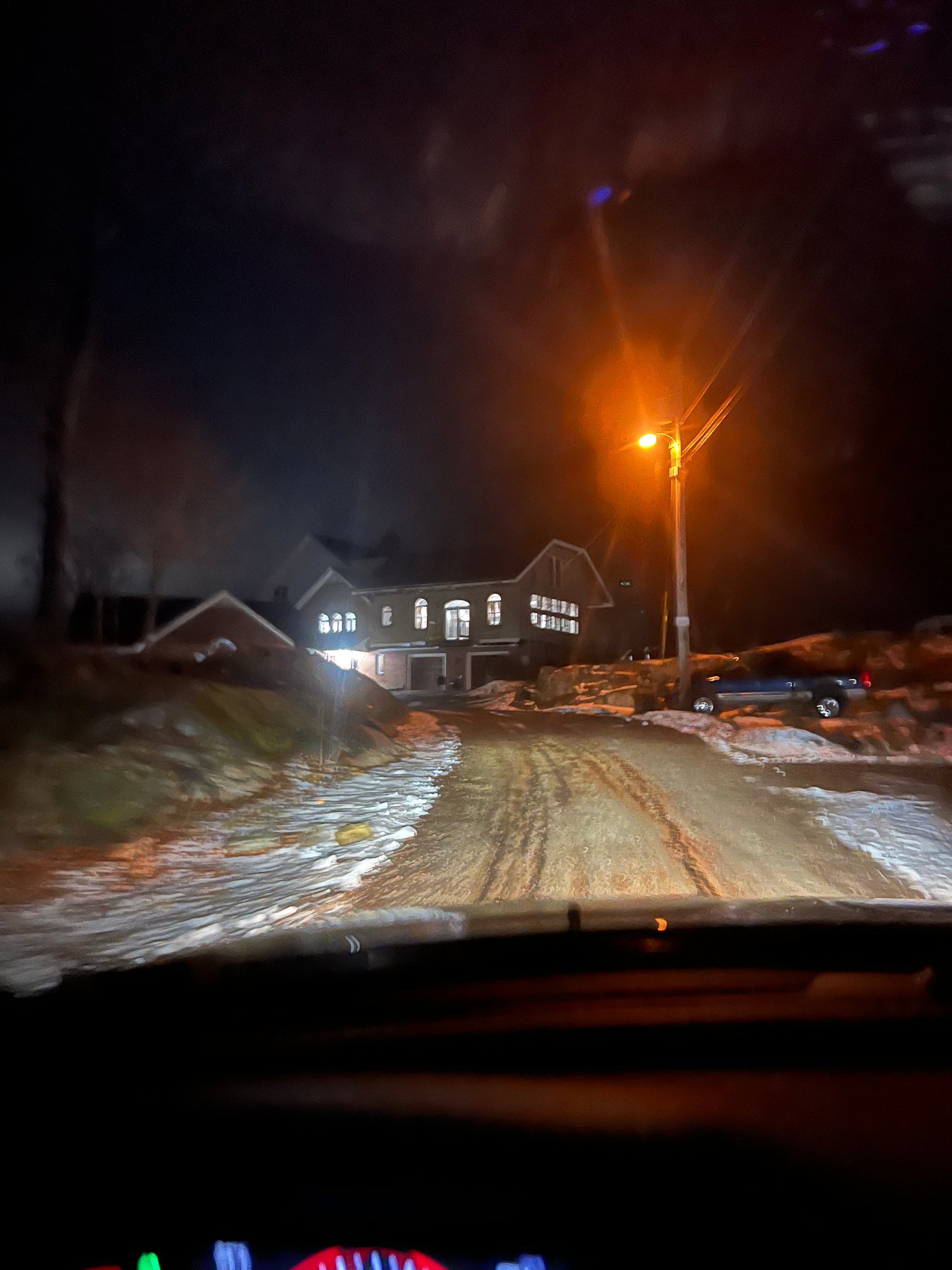Nightscape with a house and streetlight, viewed from inside a vehicle.