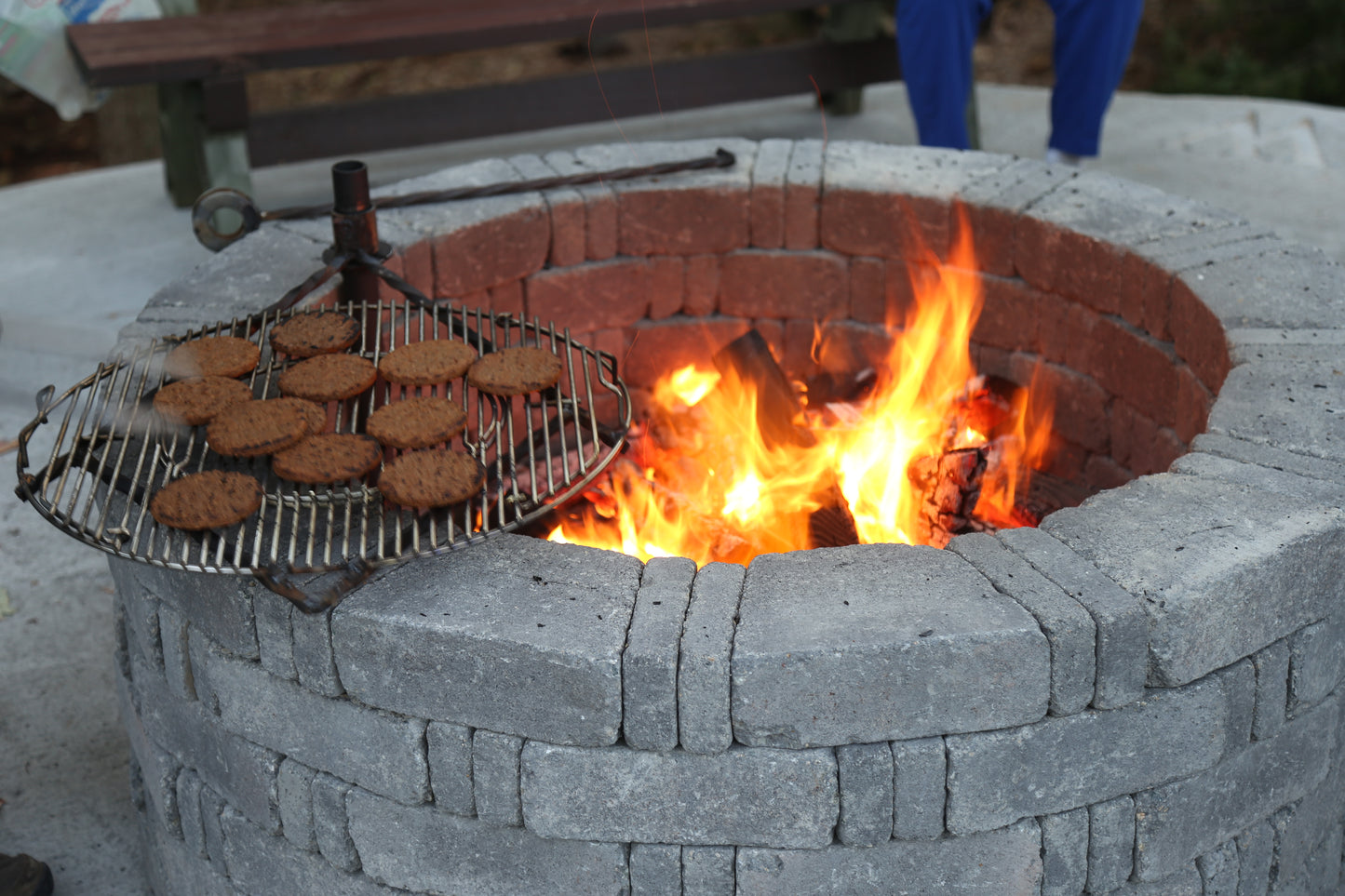 Brick fire pit with grill and food over flames, outdoor setting