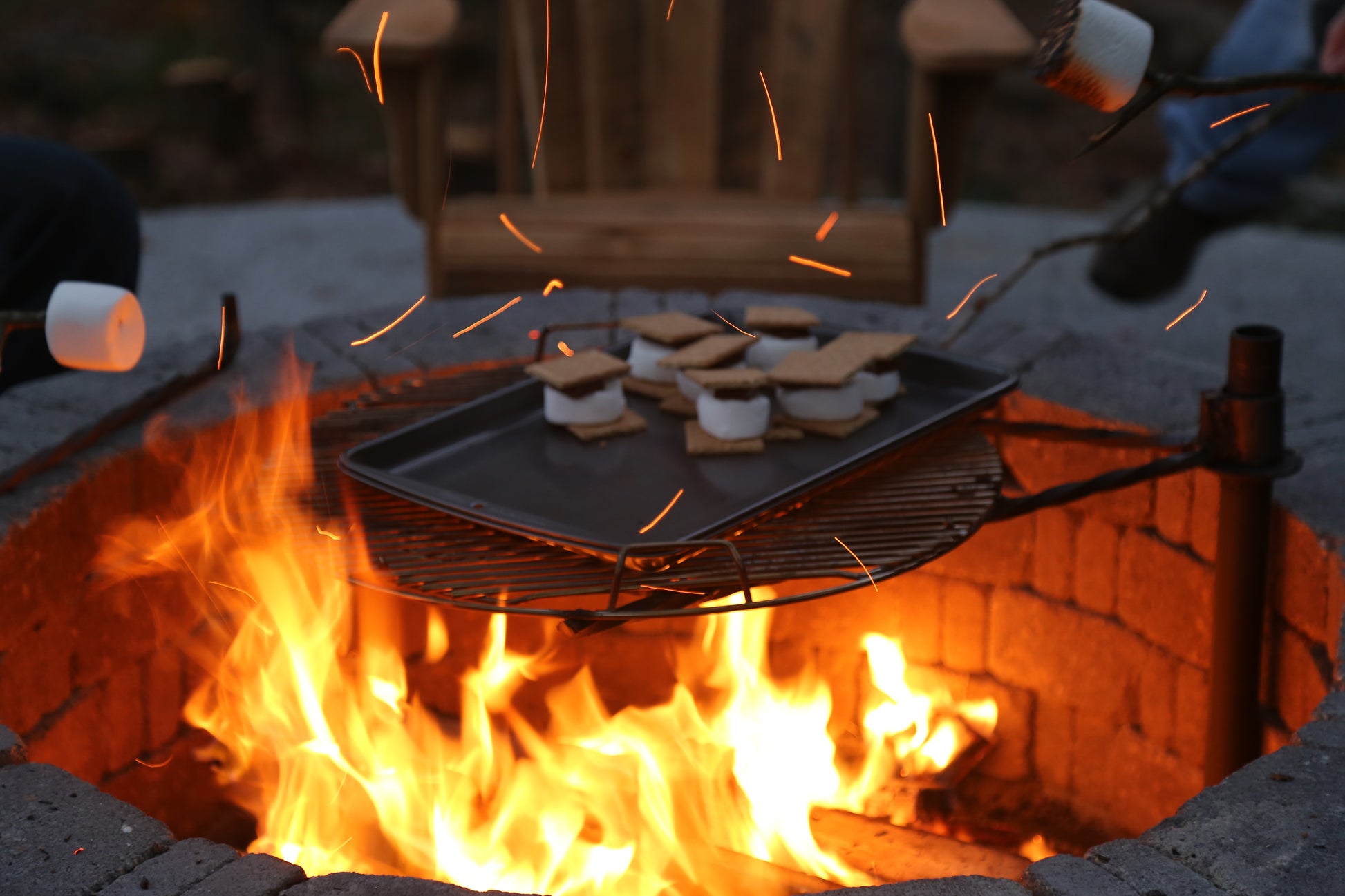 Marshmallows and graham crackers being roasted over an open fire with sparks flying. Making smores on the fire at the fire pit Nature View NH Estate 