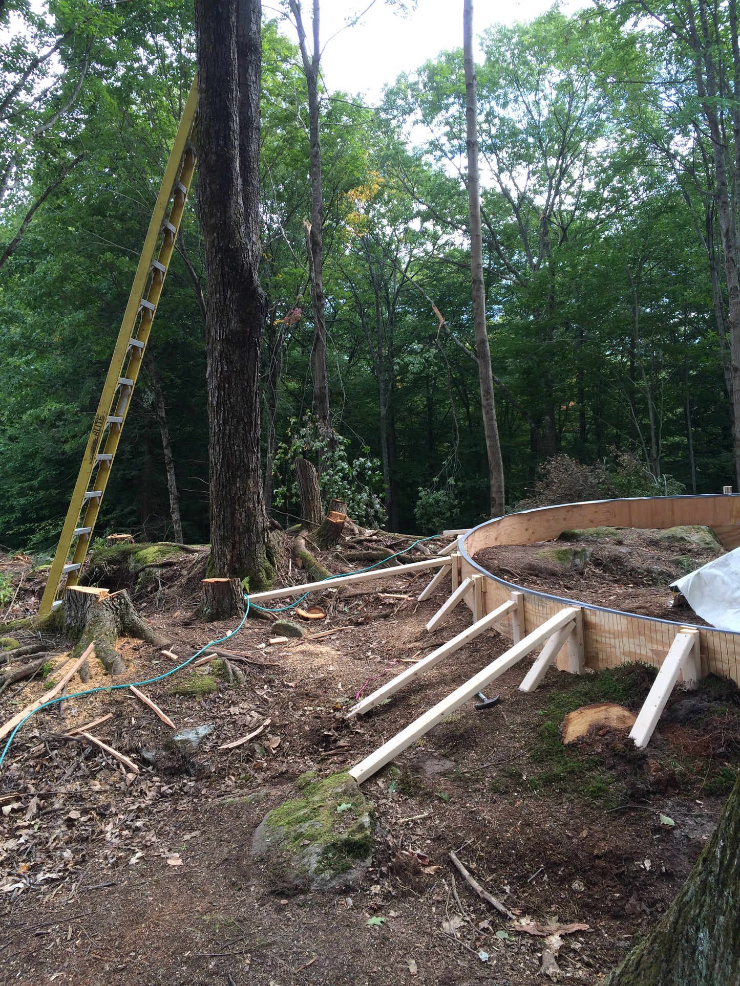 Construction of the fire pit site with wooden planks and a ladder in a forest setting