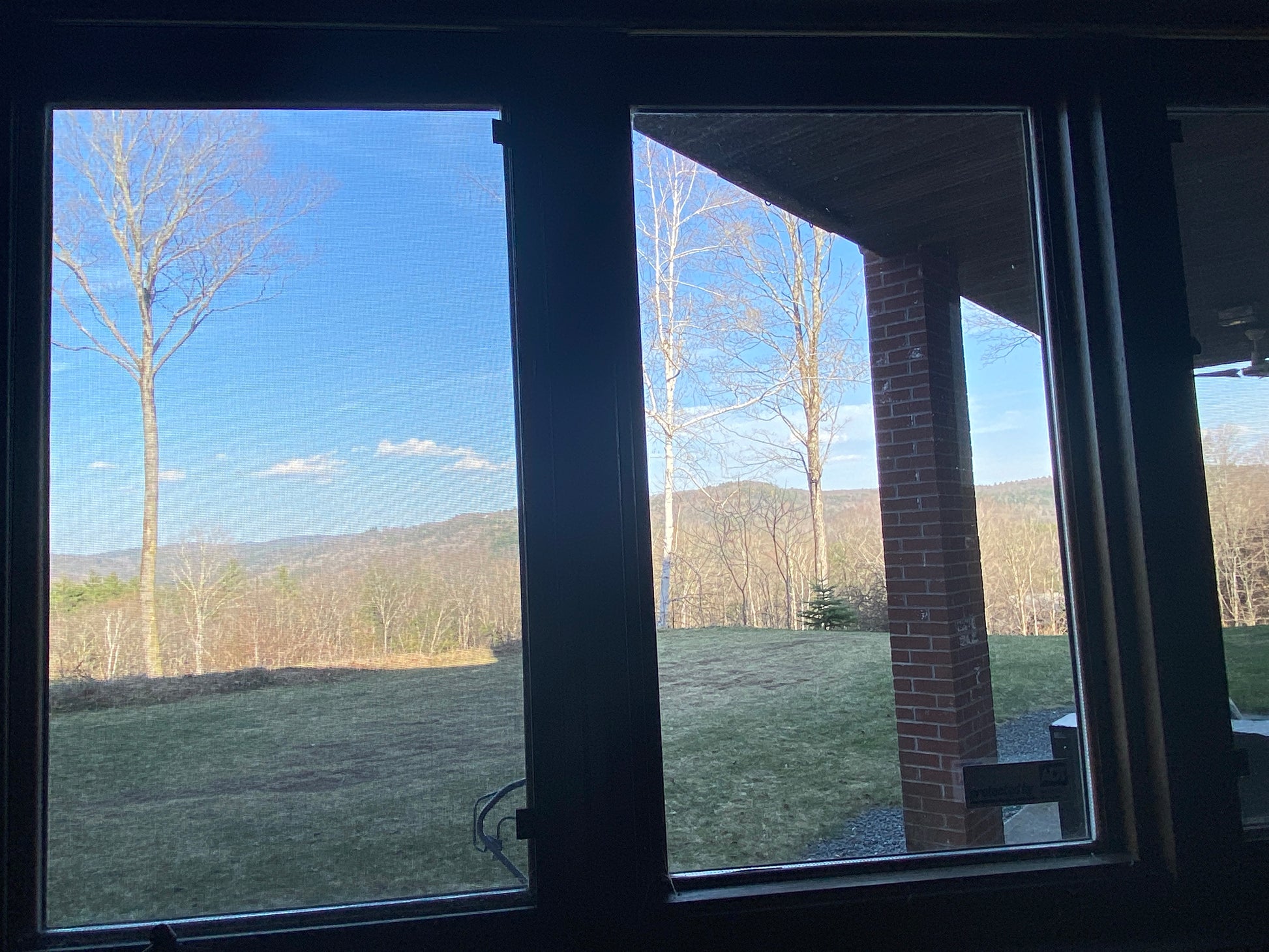 View from a window with a view of trees and mountains on a clear day.