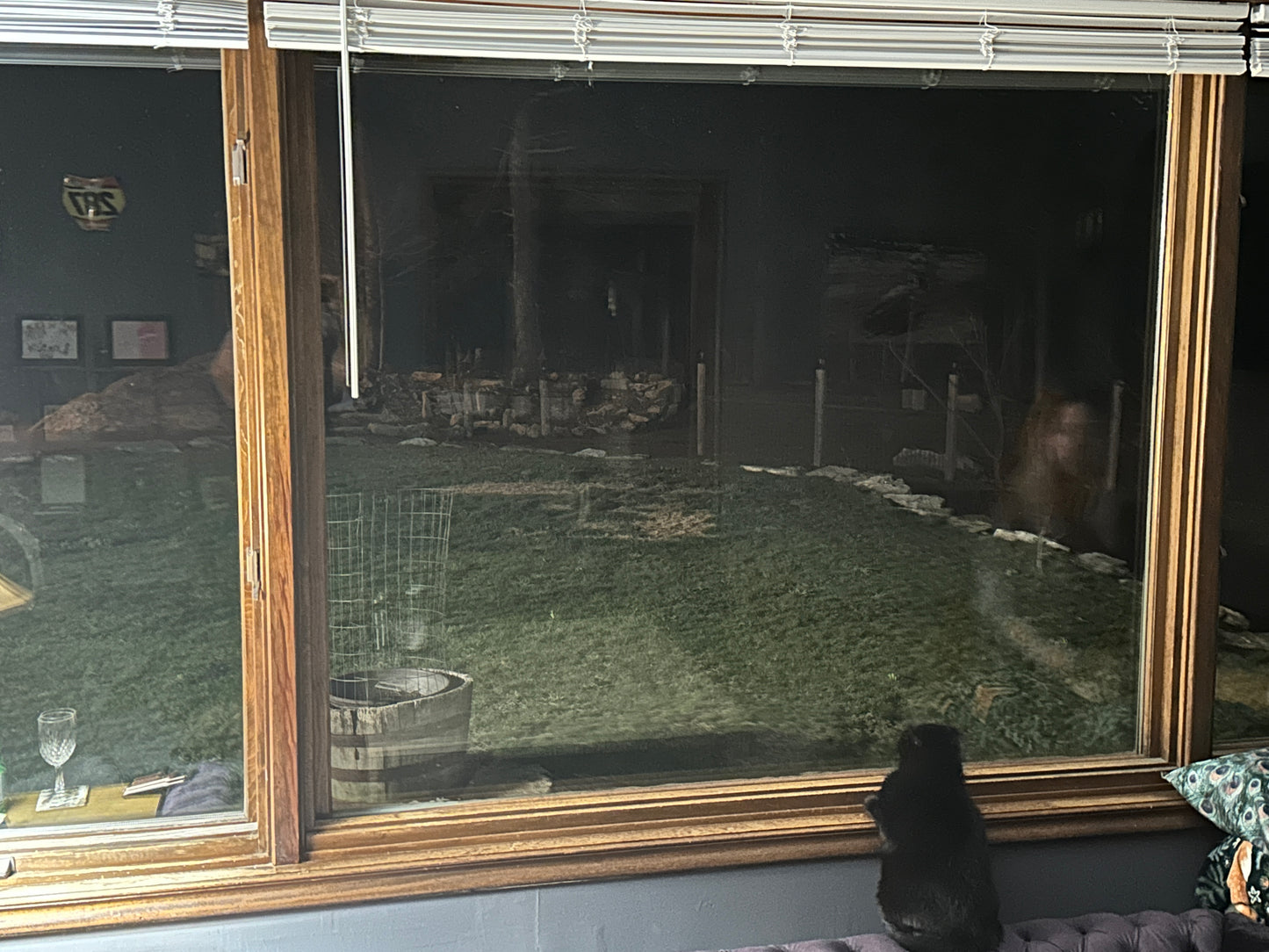 Large window with a gold frame showing a reflection of a room with furniture and decor.