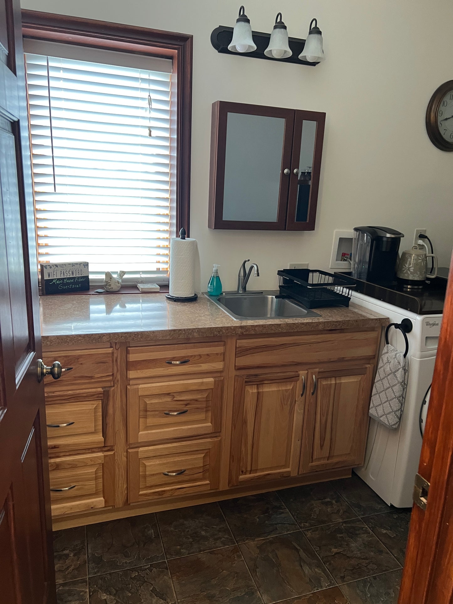 Kitchen with wooden cabinets, a window with blinds, and a countertop.