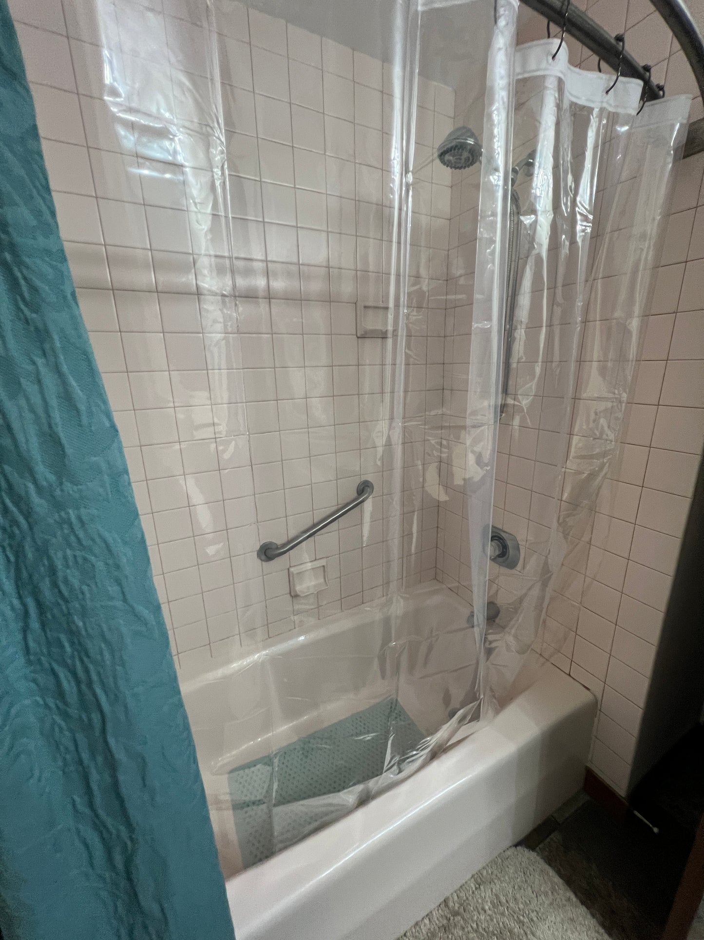 Shower enclosure with clear plastic sheeting on a tiled shower and floor.