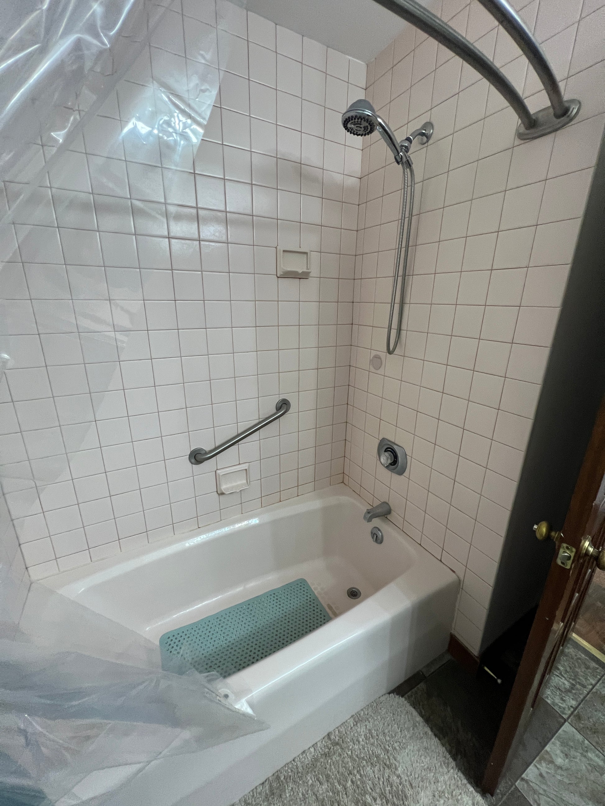 Bathroom with tiled walls, a shower head, and a bathtub.