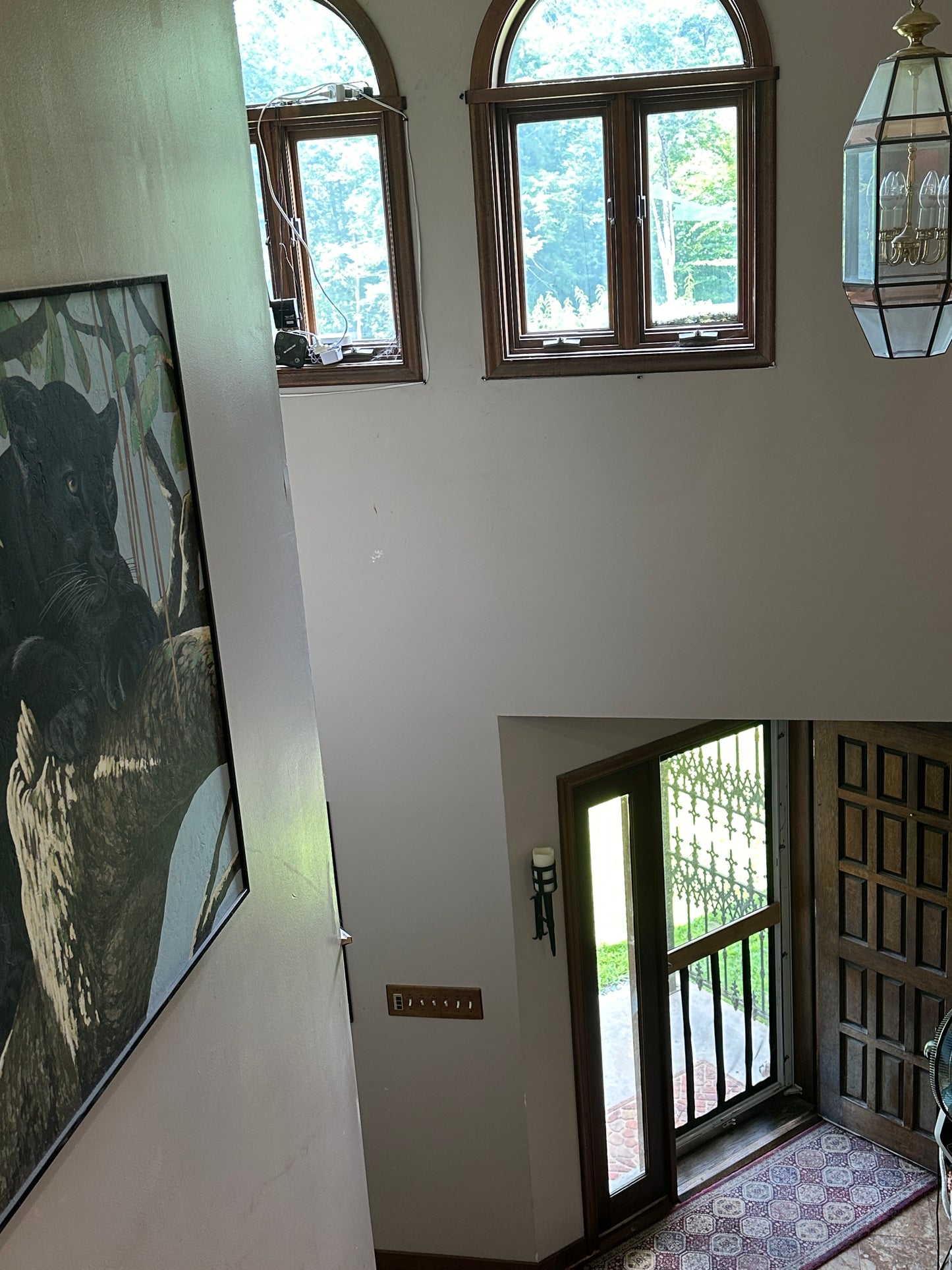 Room interior with large windows and a large painting of a panther in a tree.