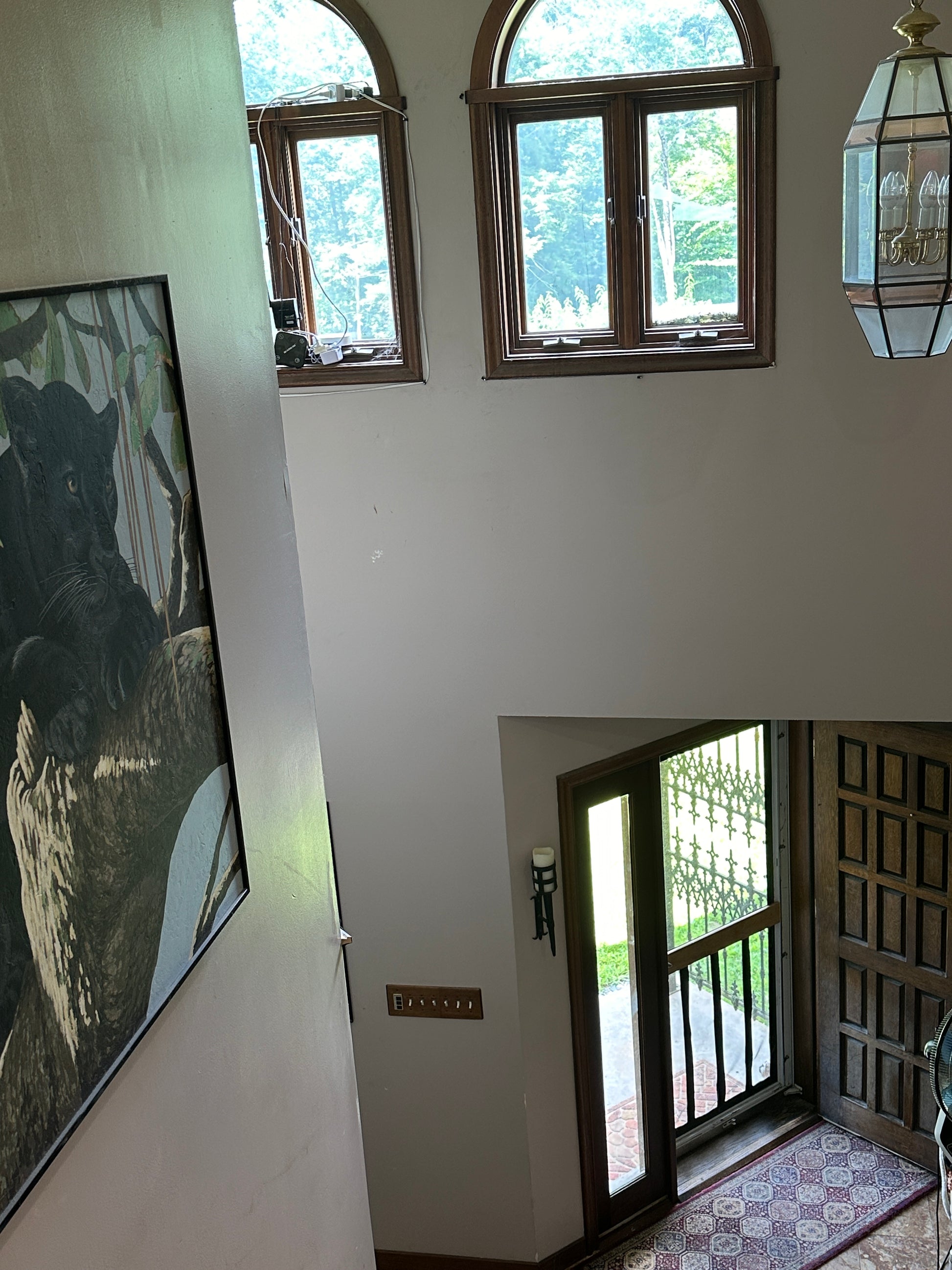 Room interior with large windows and a large painting of a panther in a tree.