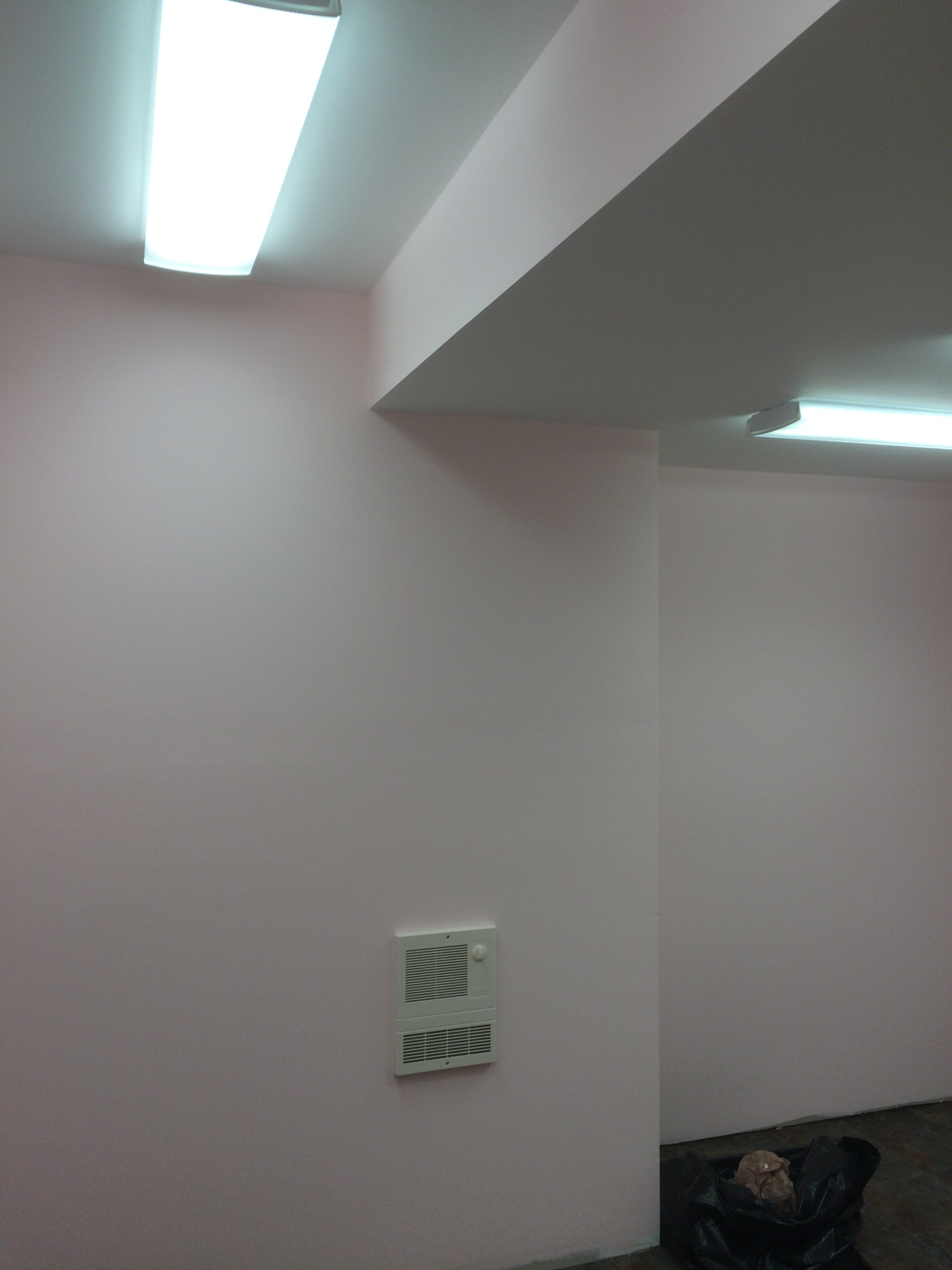 Corner of a room with a light fixture on a white wall.