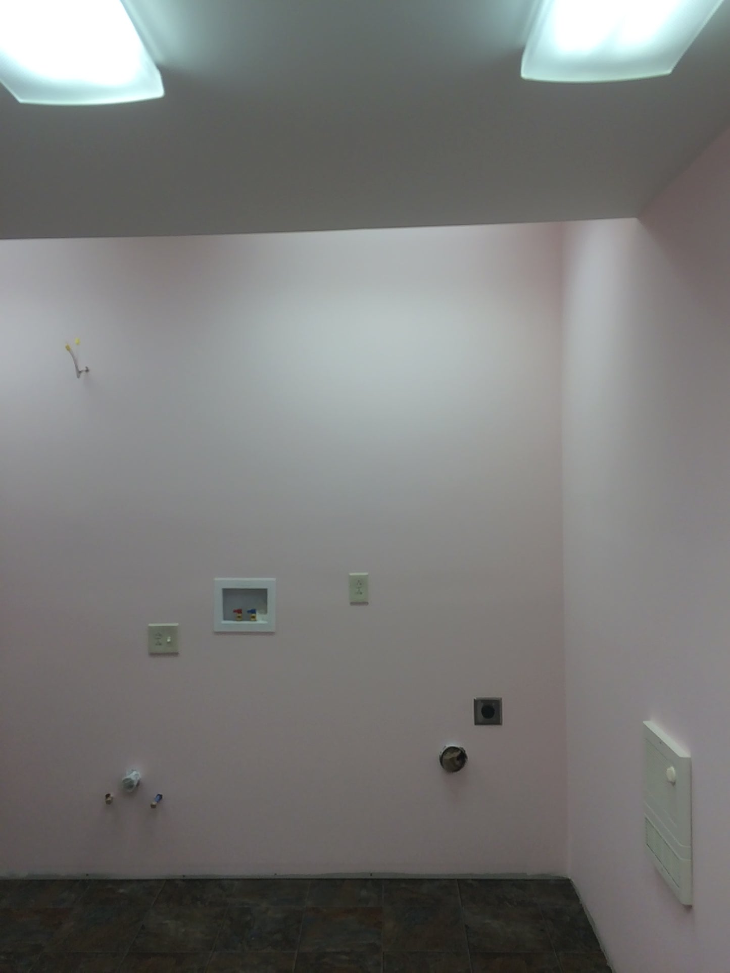 Pink wall with electrical outlets and switches in a room.