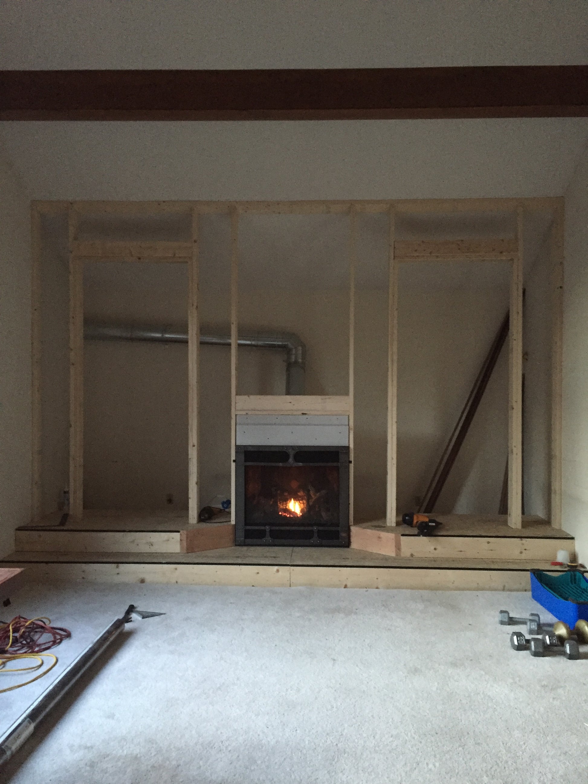 Wooden frame structure in a room with visible pipes and electrical wires.