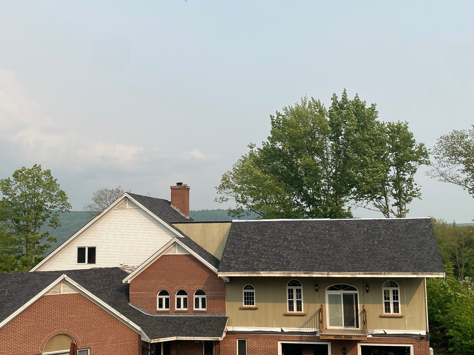 Large house with roof top deck. House with different siding sections against a clear sky