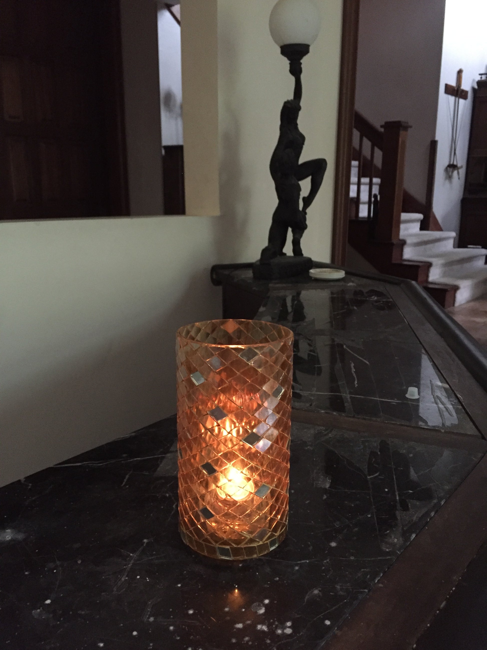 Decorative wall light fixture with textured glass shade on a dark surface.