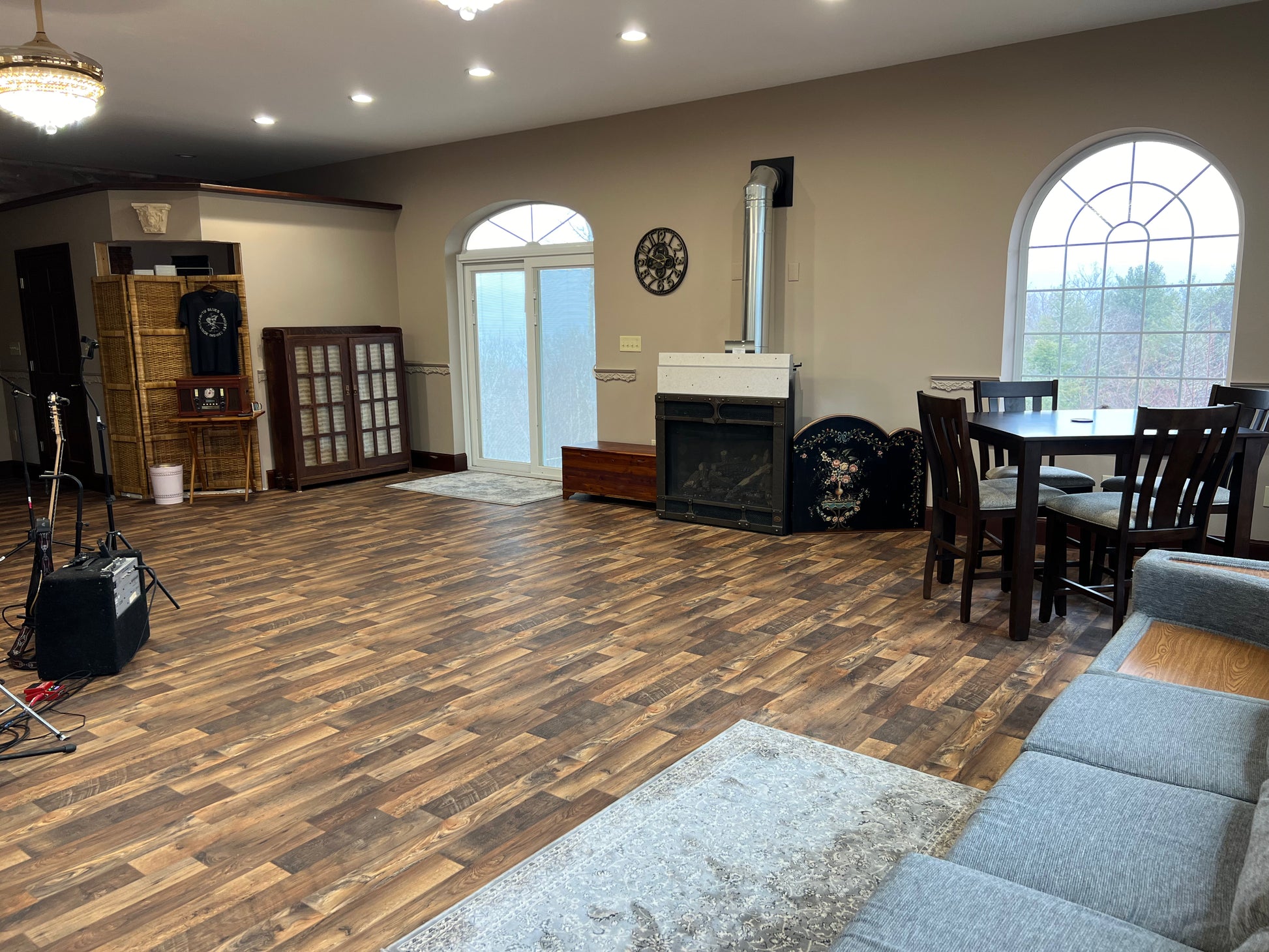 Library room with wooden flooring, gray sofa, and a fireplace.