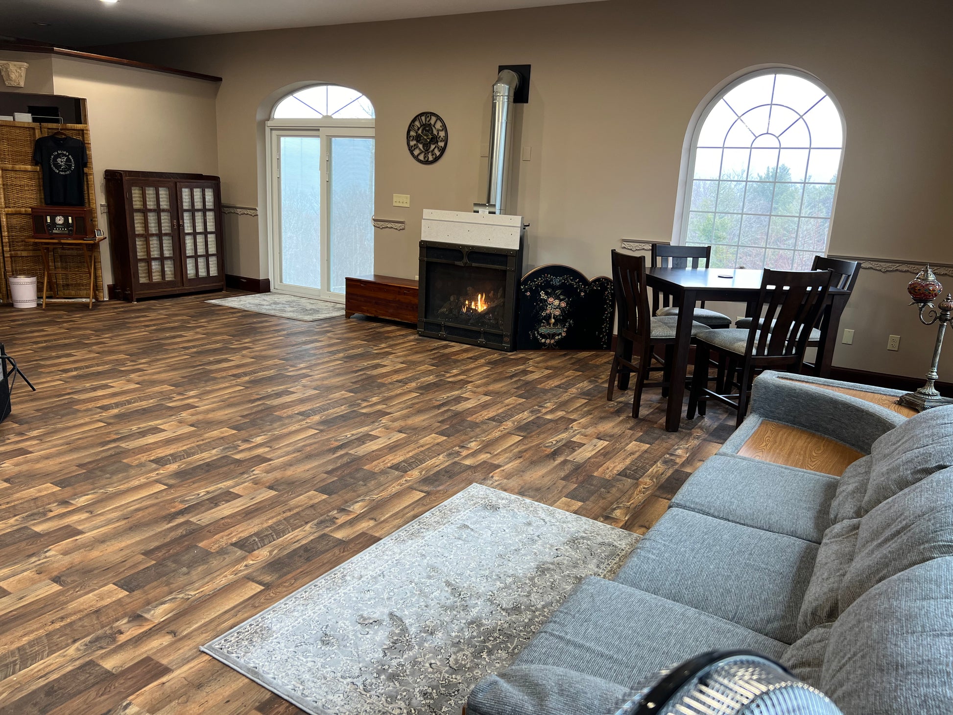 Music room with wooden flooring, gray sofa, and a fireplace.