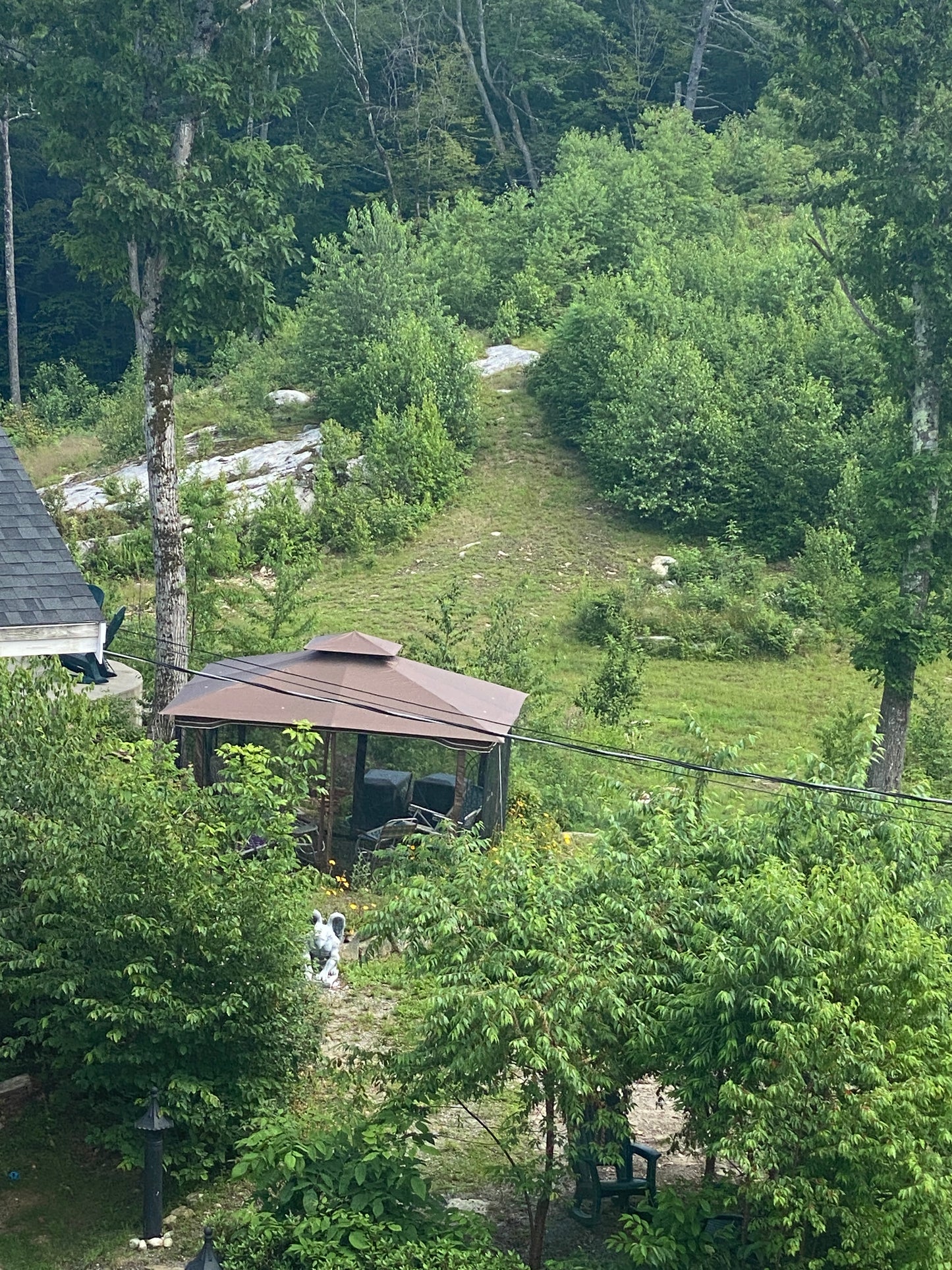 Aerial view of a patio surrounded by trees and grass. Trails in the background