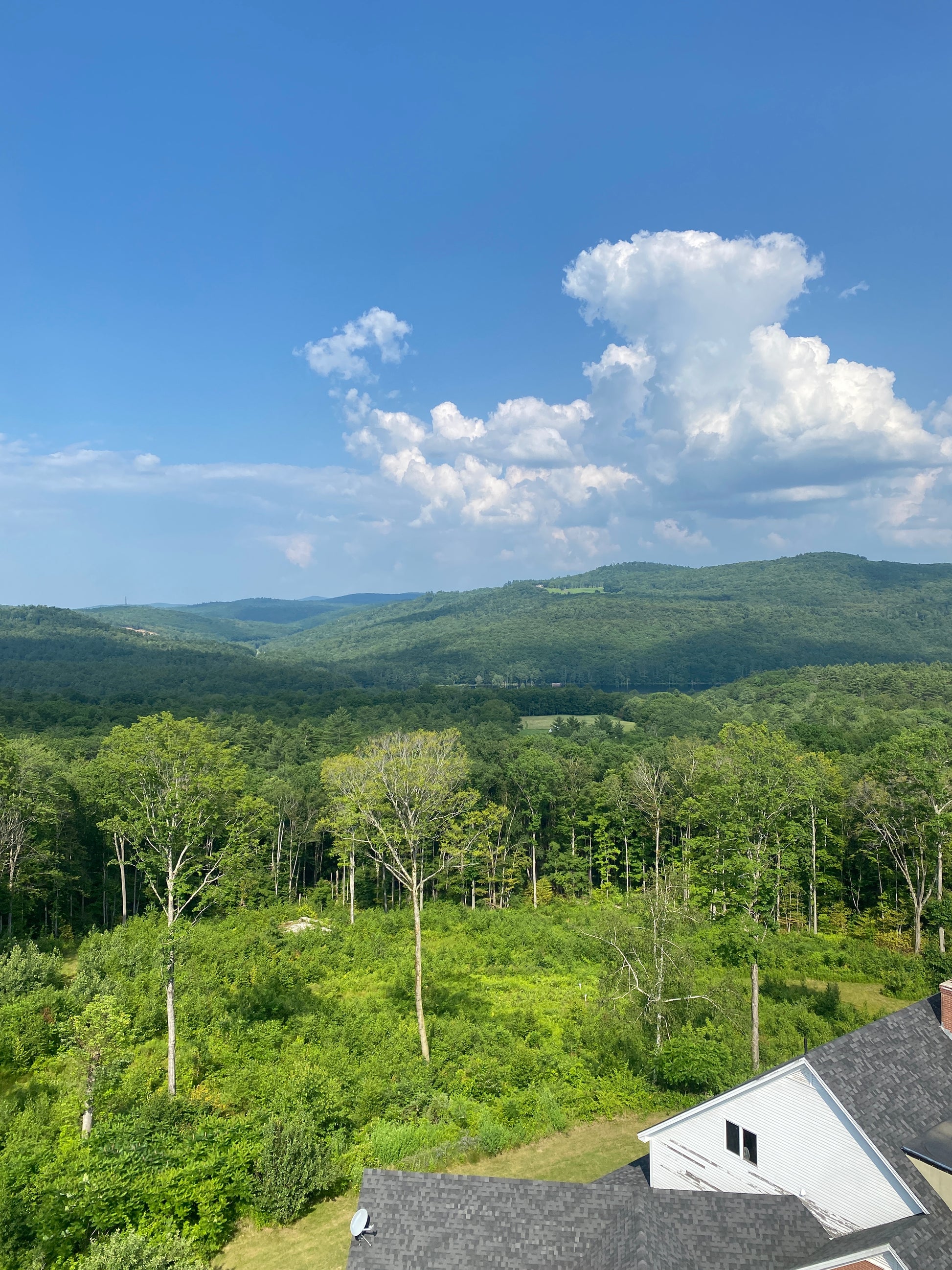 Scenic view of a mountain with a clear blue sky and a house on the right.