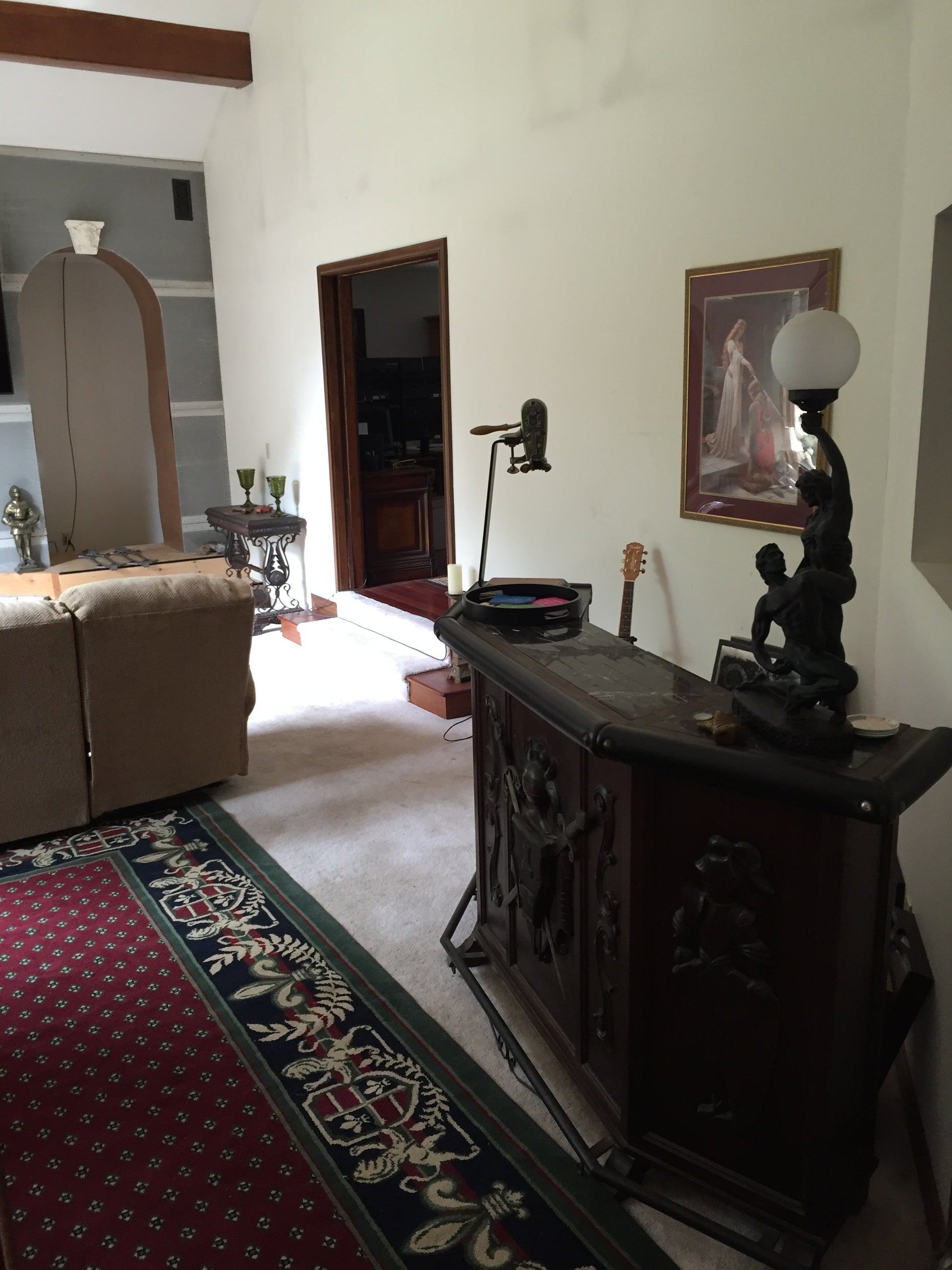 Decorative interior with a black ornate object, lamp, and framed picture on a white wall.