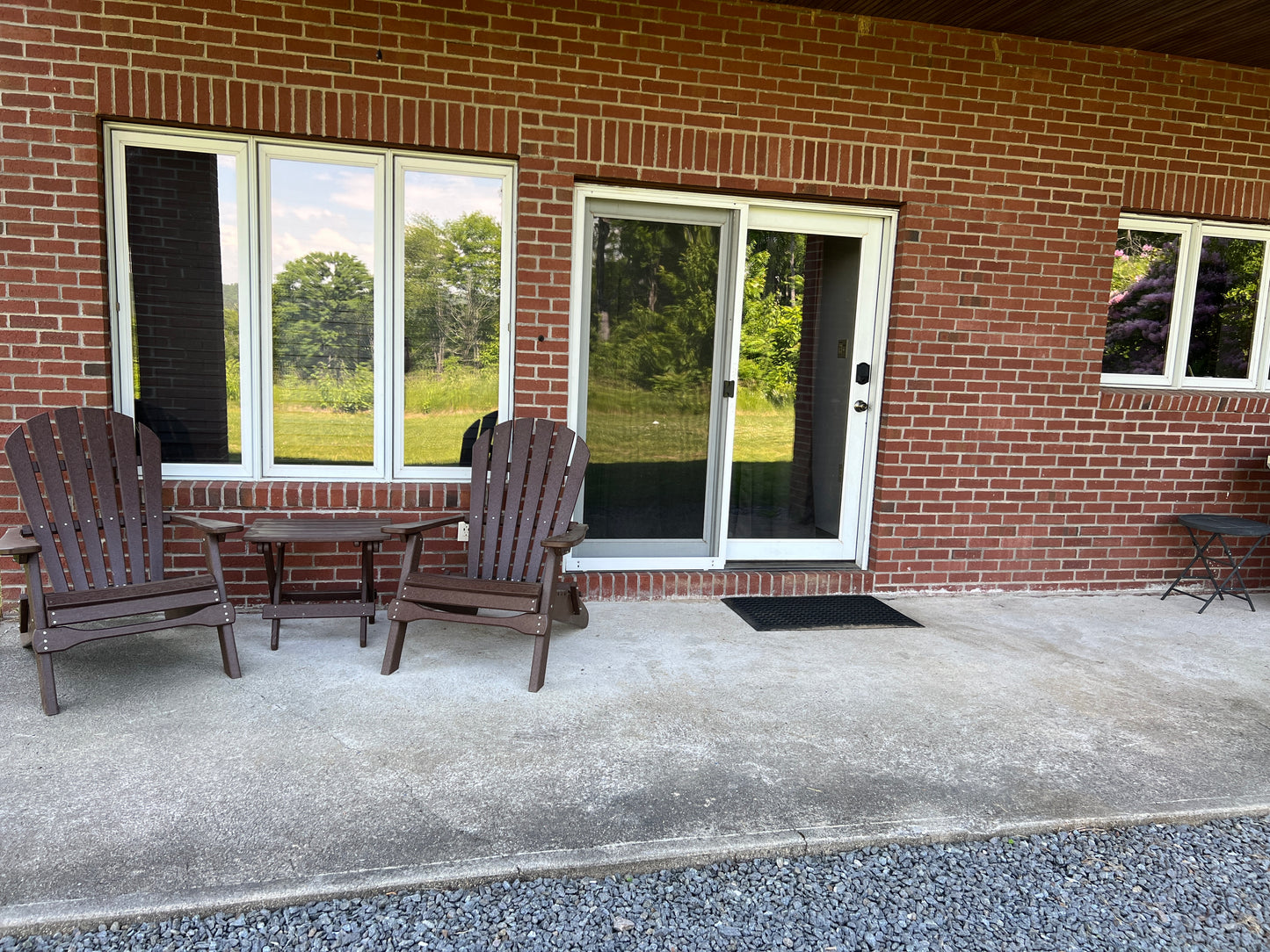 Outdoor seating area with chairs and a table in front of a brick building with windows.