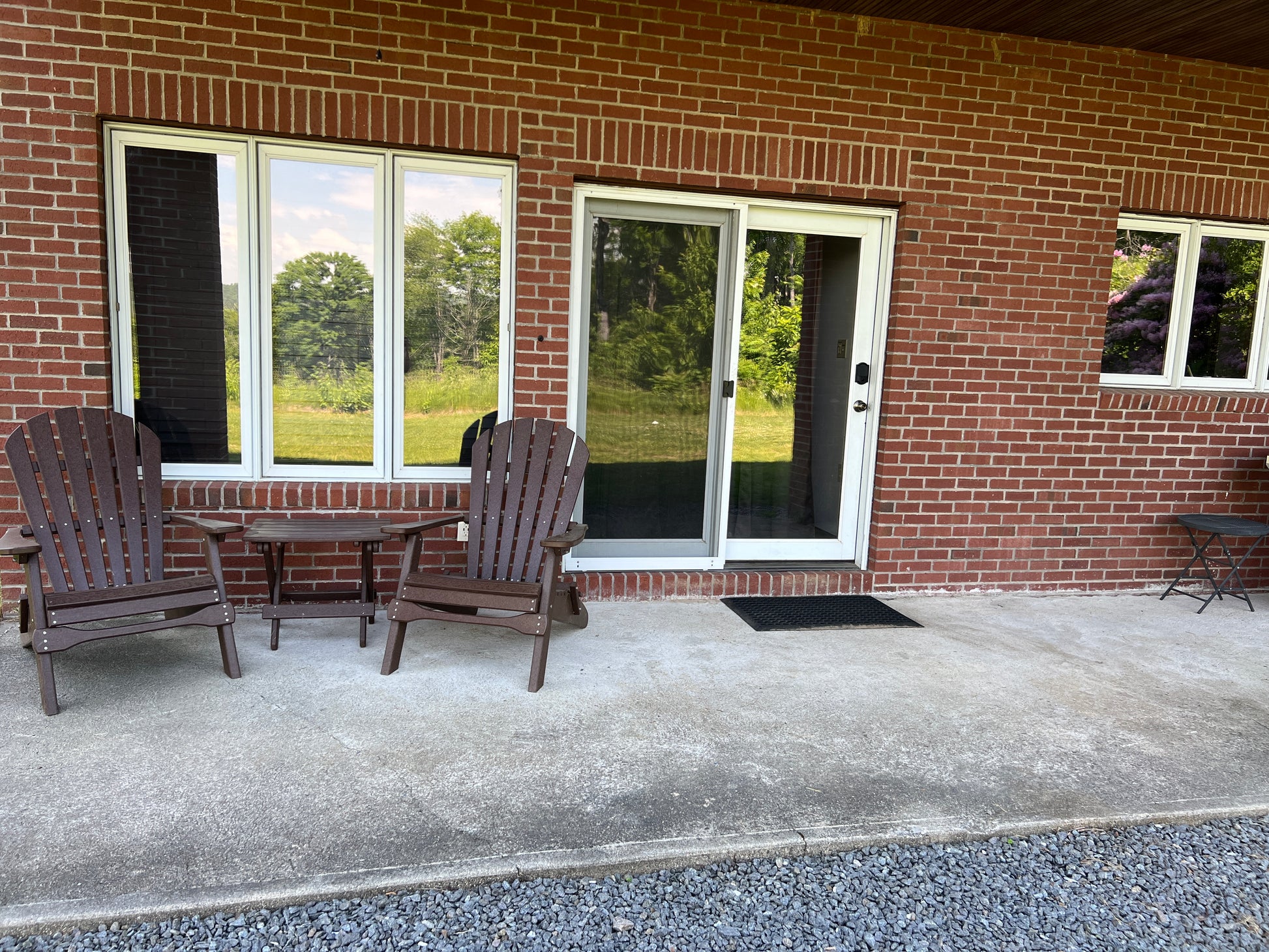 Outdoor seating area with chairs and a table in front of a brick building with windows.