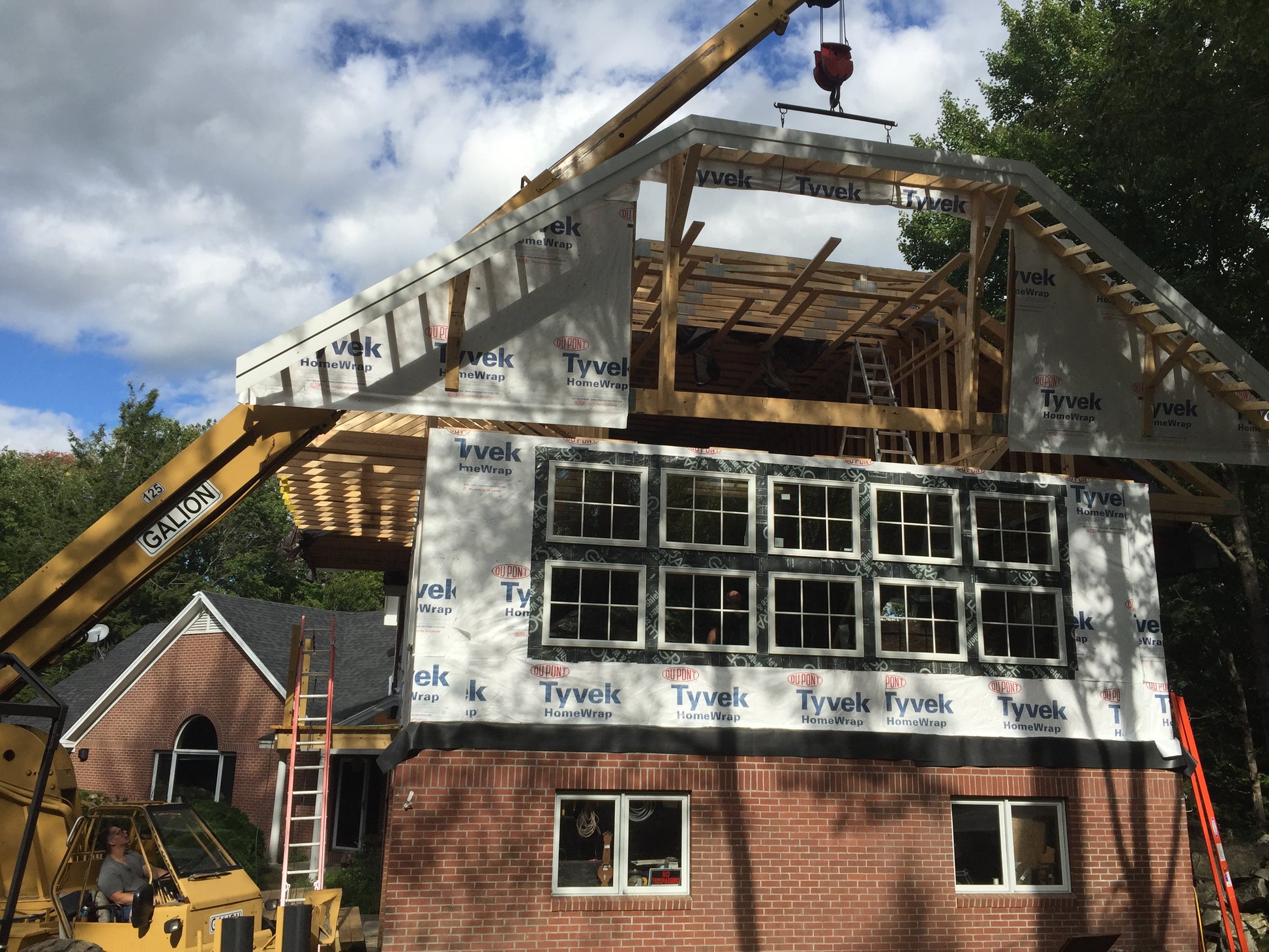 Building the library under construction with wooden frame and Tyvek siding, crane in the background. Notice the large room being  above the library