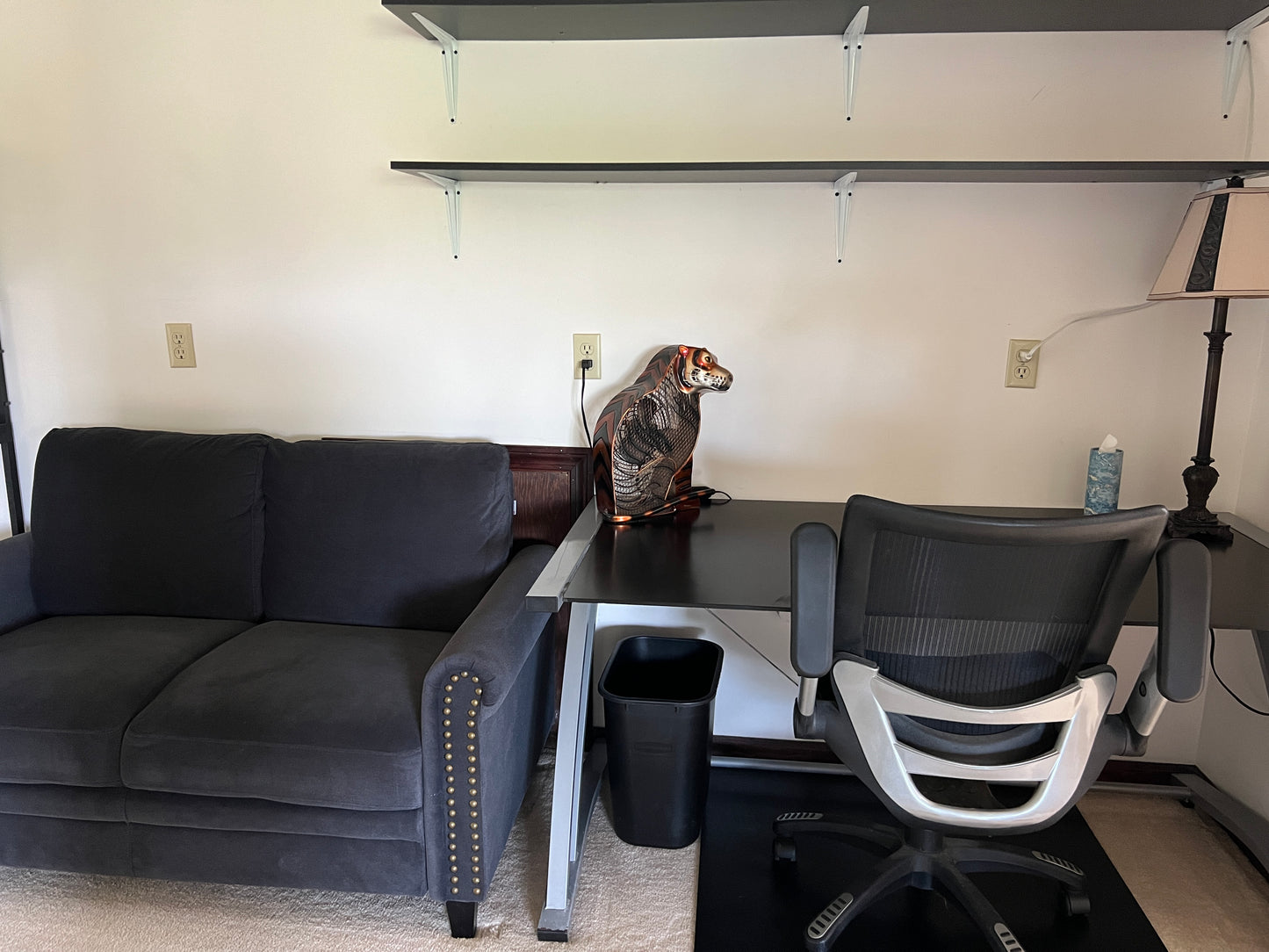 Living room with gray sofa, desk, chair, and decorative items.