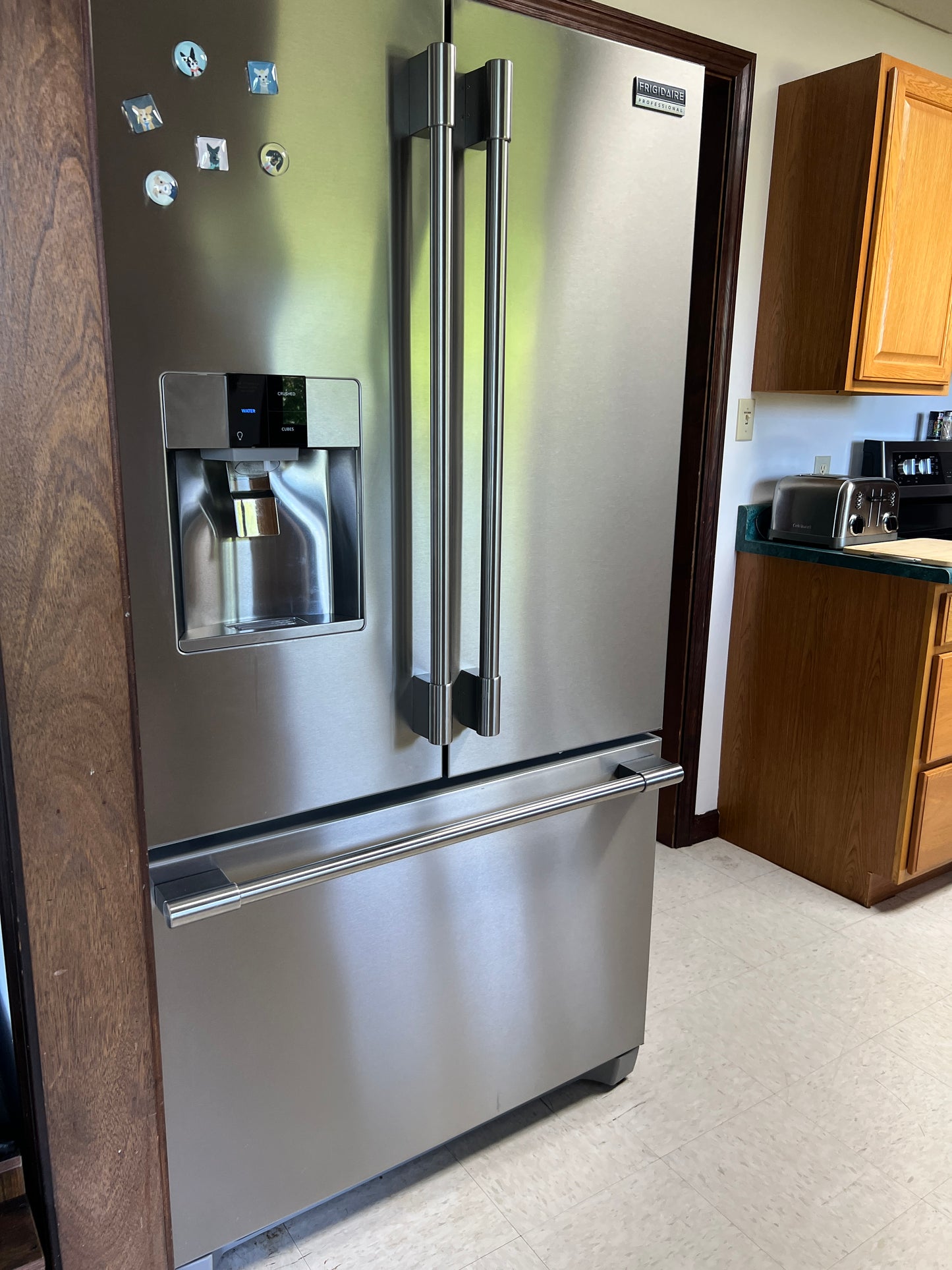 Stainless steel refrigerator with water and ice dispenser on a kitchen counter.