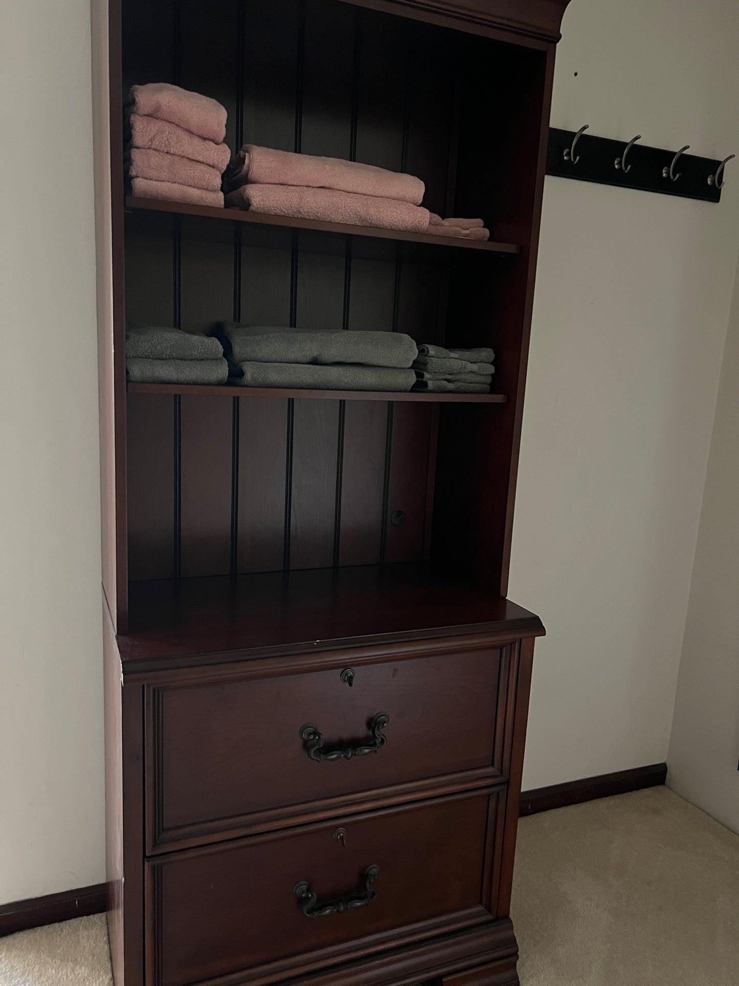 Open wooden wardrobe with clothes inside, mounted on a wall.