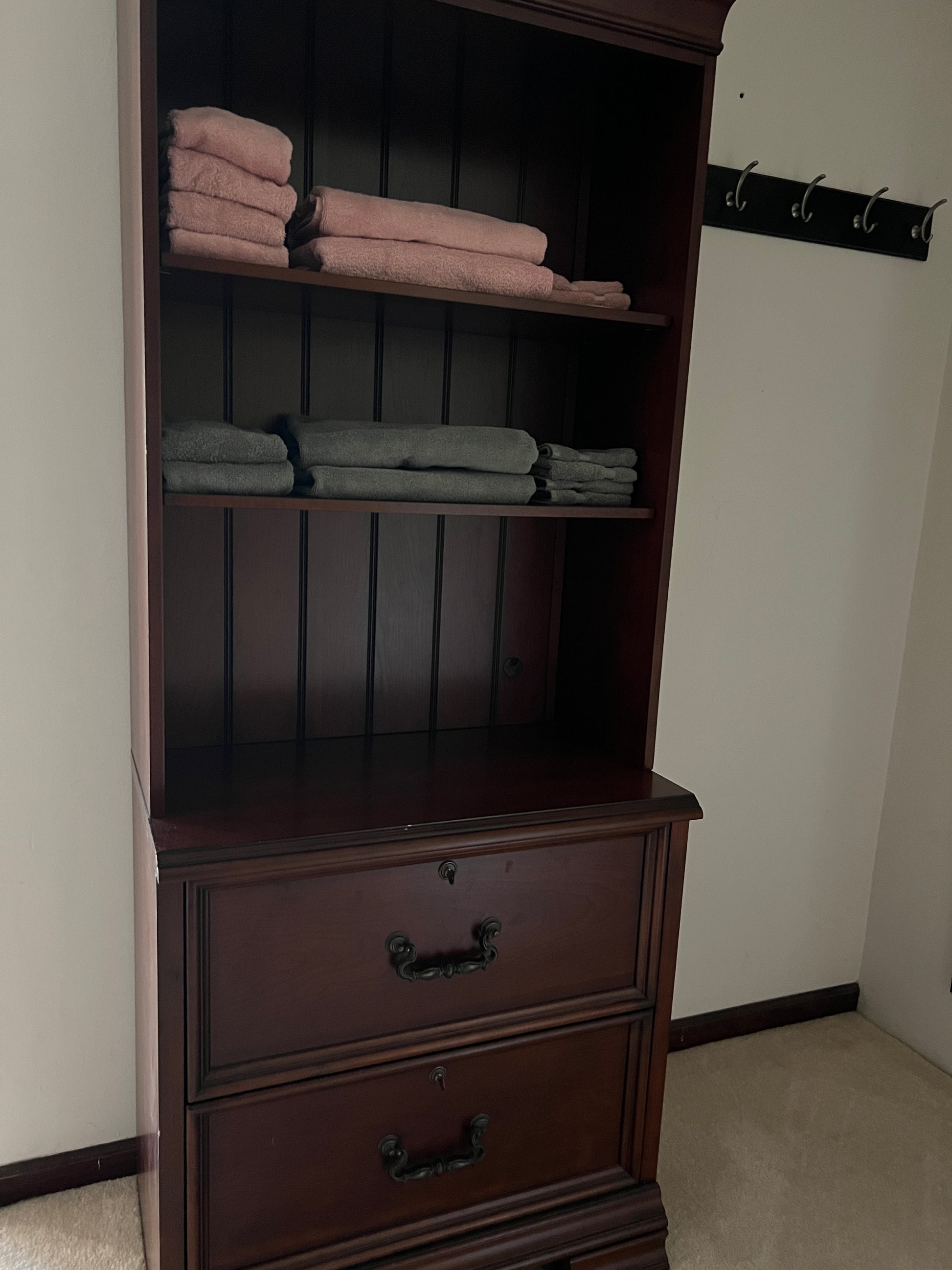 Open wooden wardrobe with clothes inside, mounted on a wall.